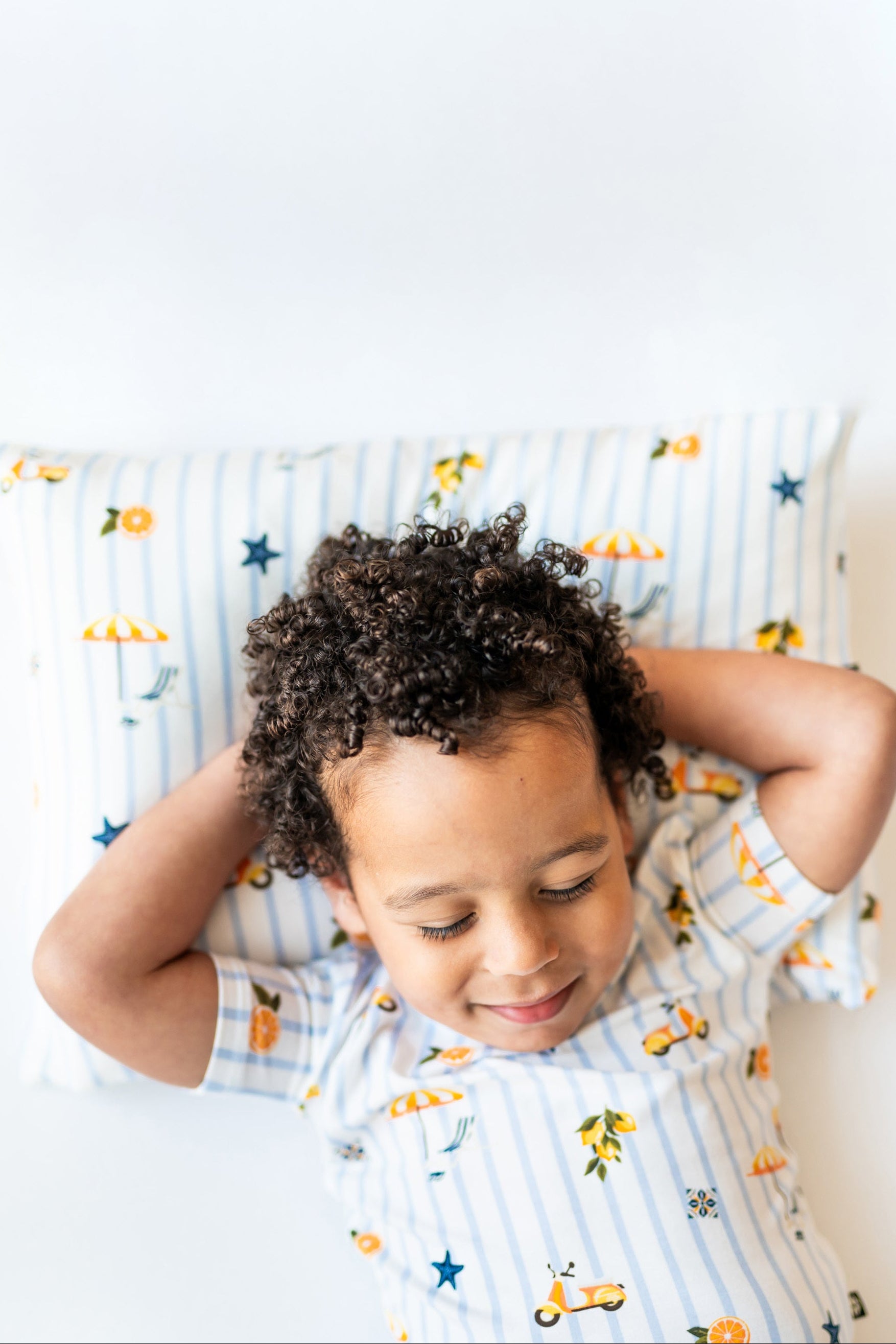Toddler sleeping on a toddler pillow with a case that features amalfi coast inspired icons and blue stripes