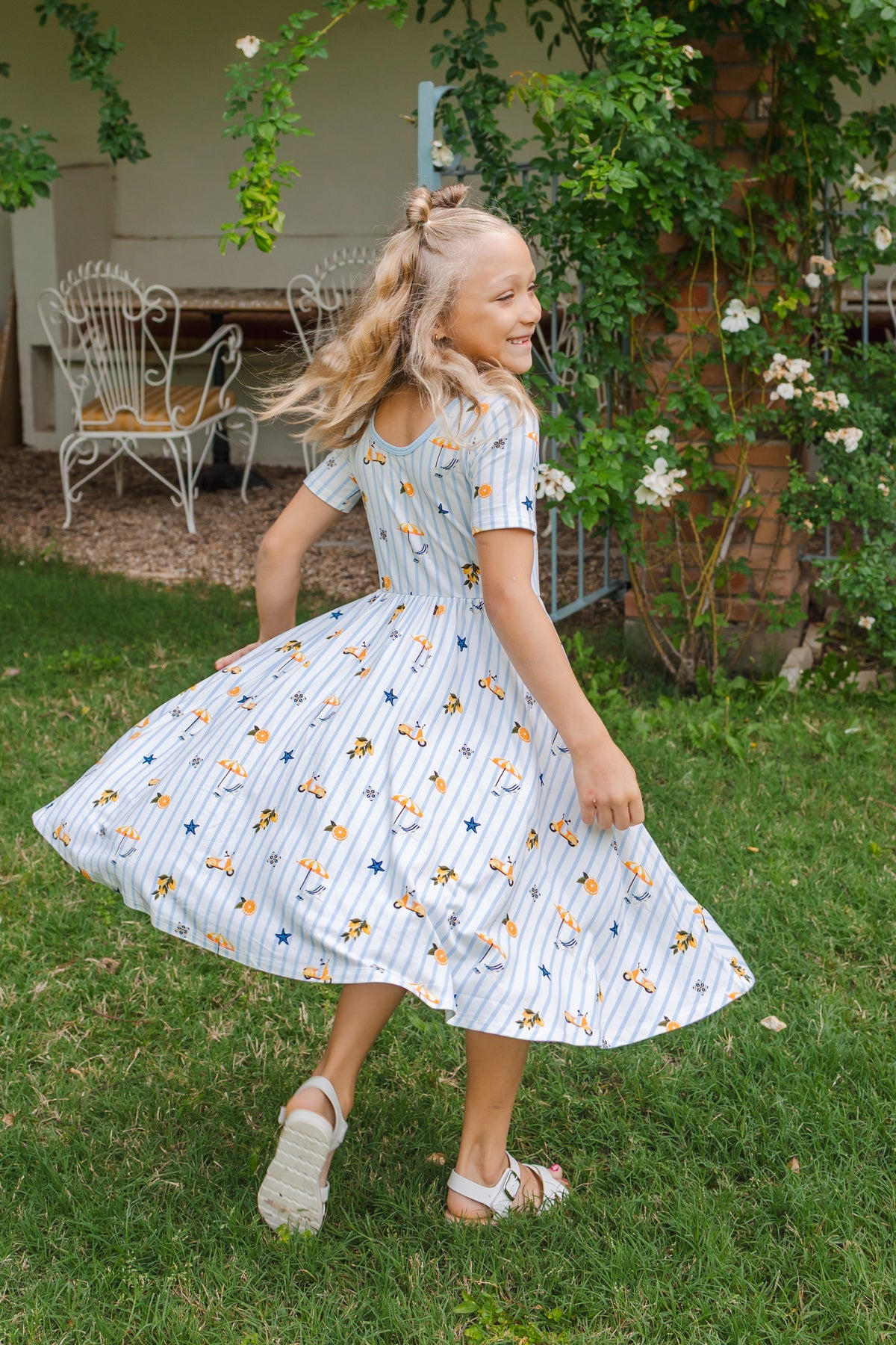 Girl twirling in a short sleeve dress with blue stripes and amalfi coast inspired icons 