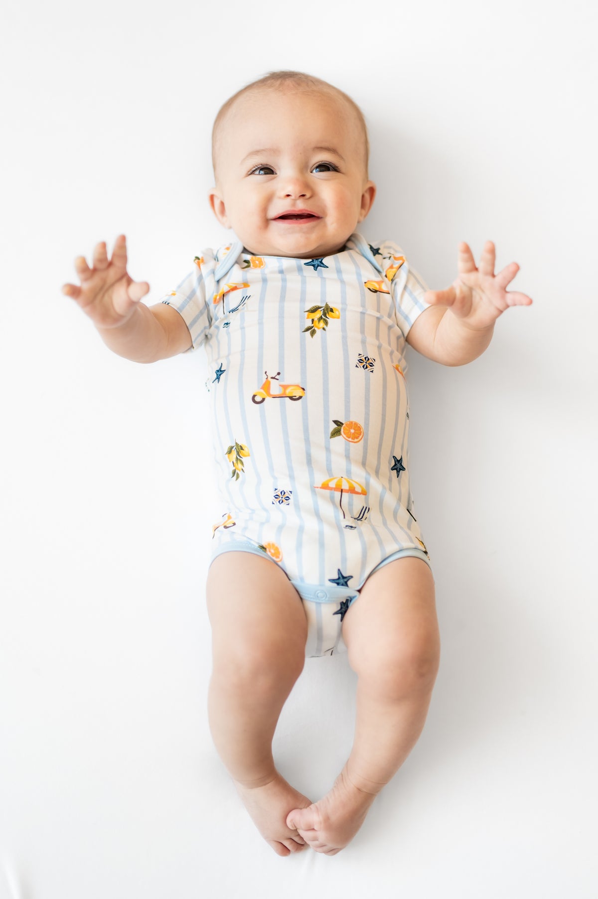 Infant wearing the Bodysuit in Amalfi Coast laying on a white surface