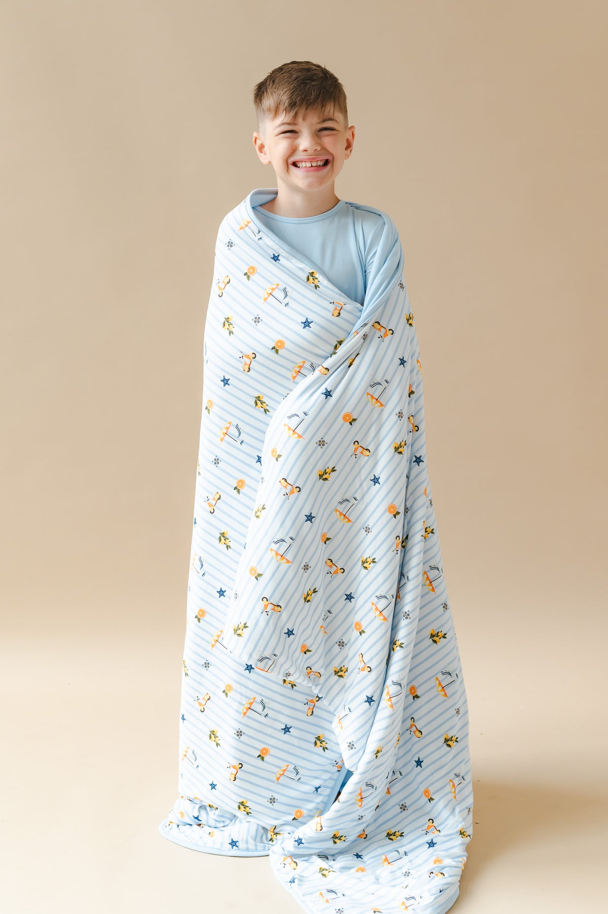 Young smiling boy standing with the Youth Blanket in Amalfi Coast 1.0 around him