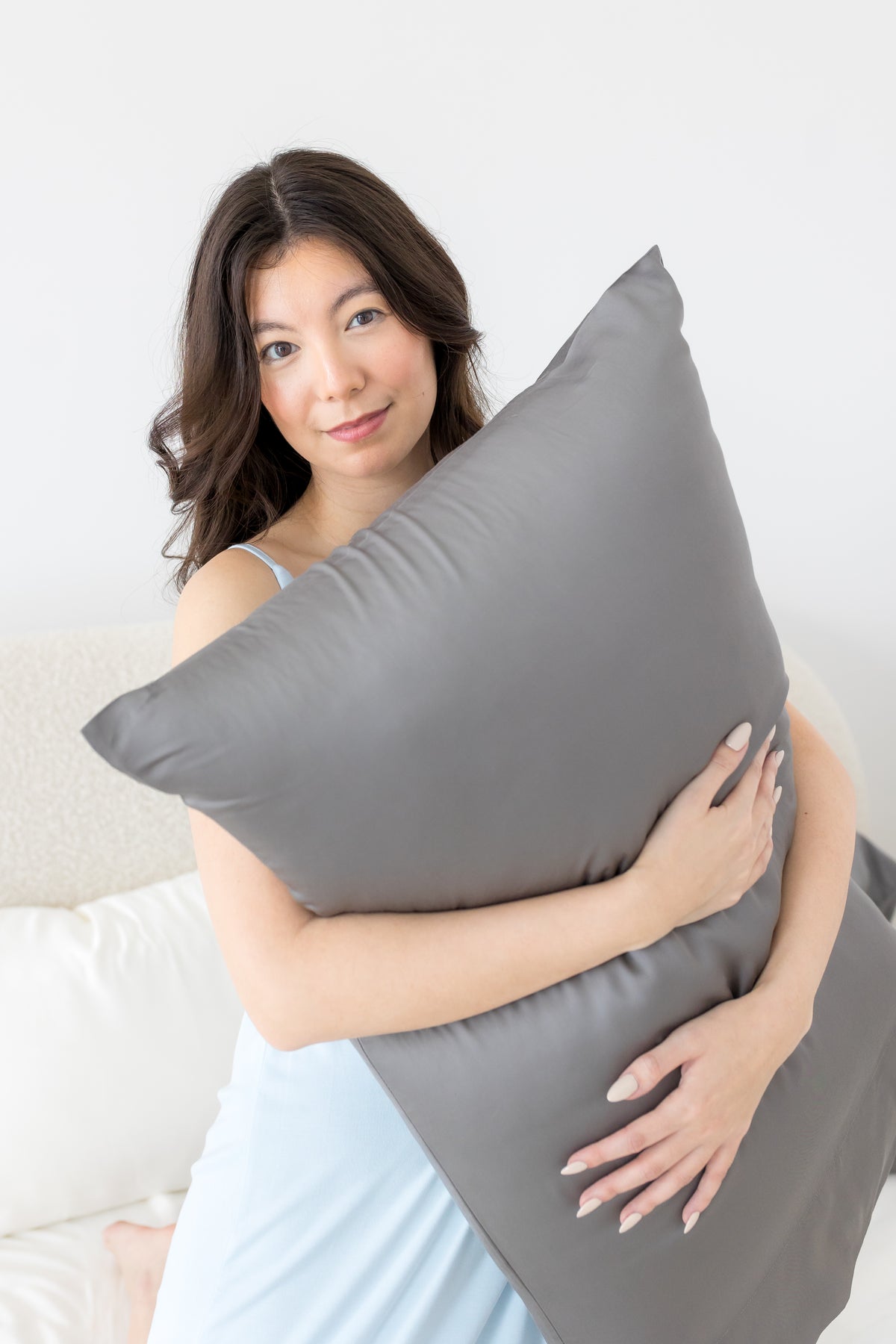 Female holding a pillow with the Bamboo Sateen Pillowcase in Ash on it