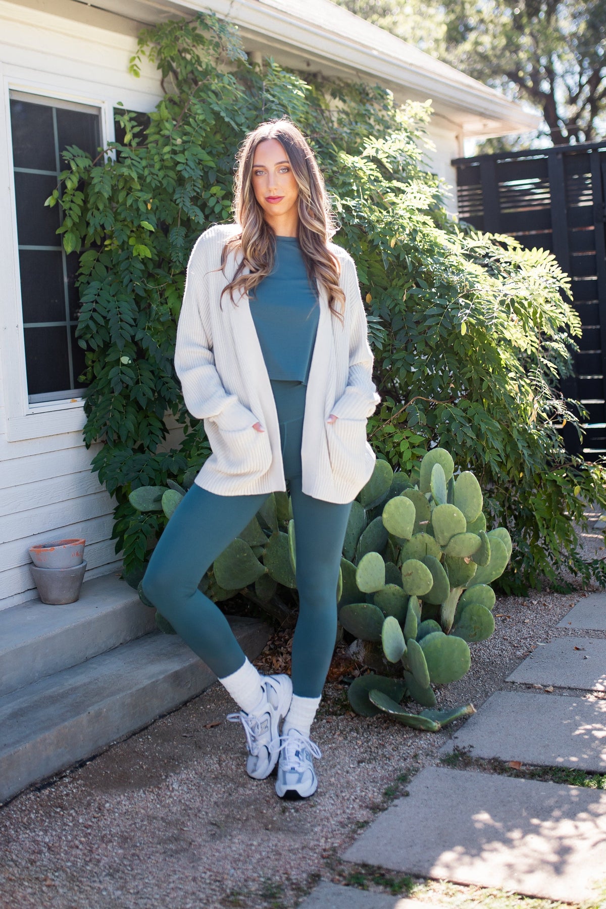Model wearing the Bamboo Flex Women’s Leggings in Atlantic with matching short sleeve tee with an oat Chunky Knit oversized cardigan overtop