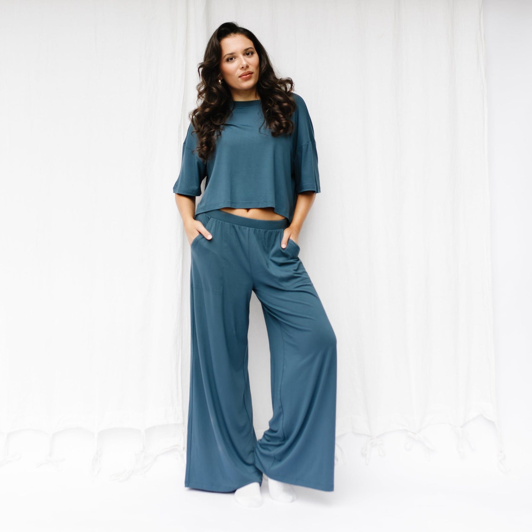 Female model standing in front of a white backdrop wearing the Women's Wide Leg Pant in Atlantic and matching Short Sleeve Tee
