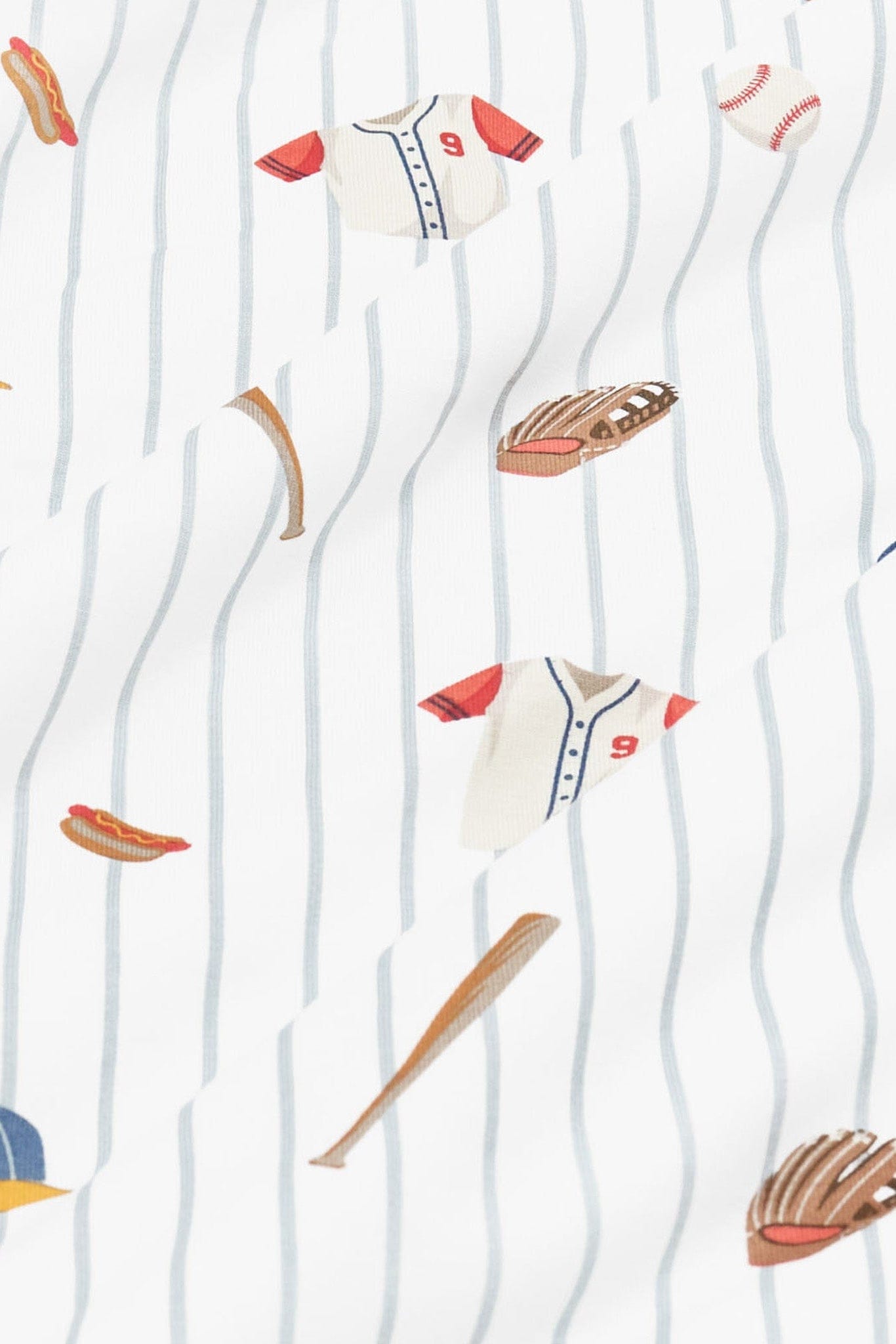 Close up of bamboo fabric: An all-over print featuring baseballs, wooden baseball bats, catcher’s mitts, white baseball jerseys with red sleeves and a red number 9, blue baseball caps with a yellow brim, and a hot dog, over a white background with dusty blue pinstripes.