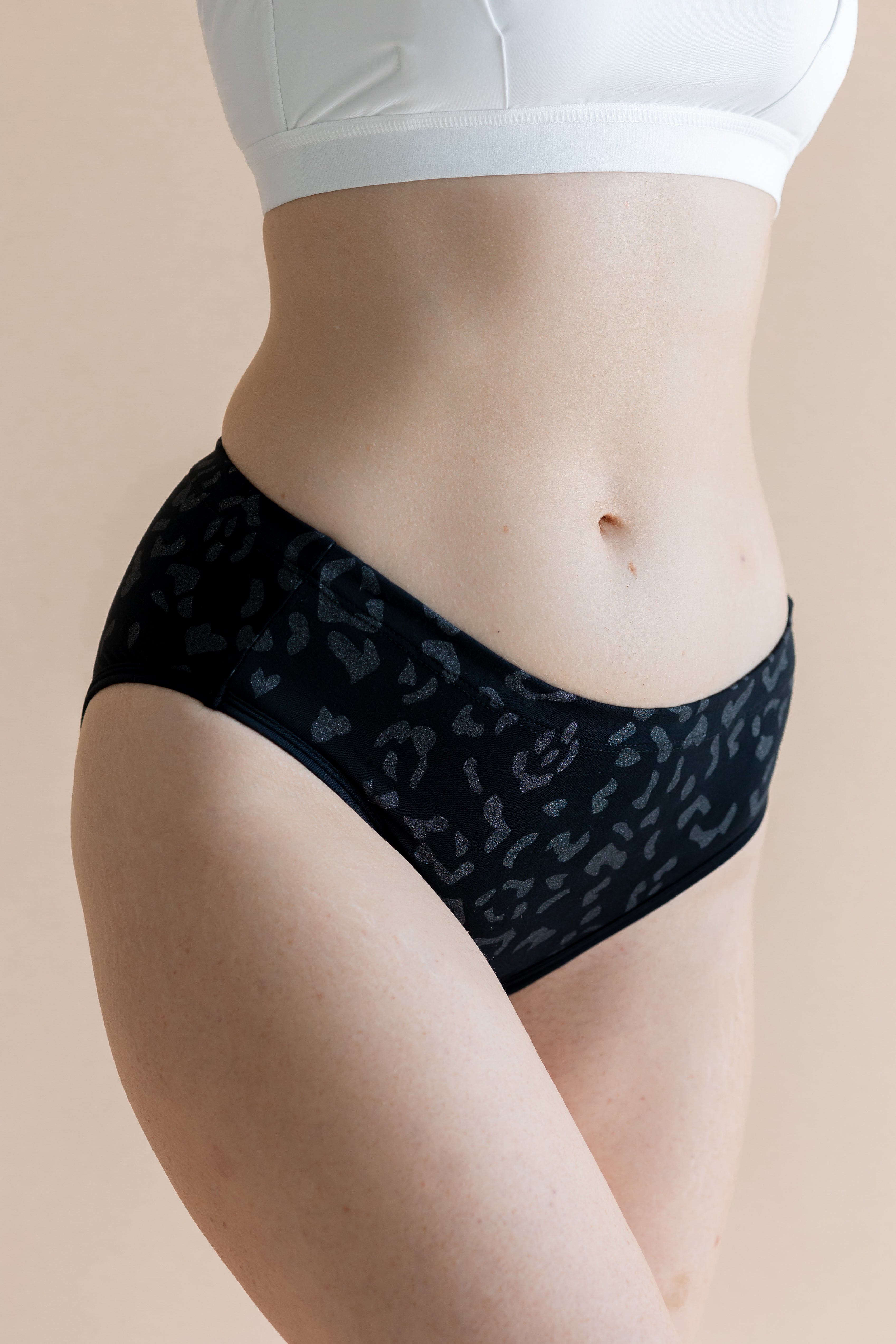 Person wearing black leopard patterned underwear on a beige background