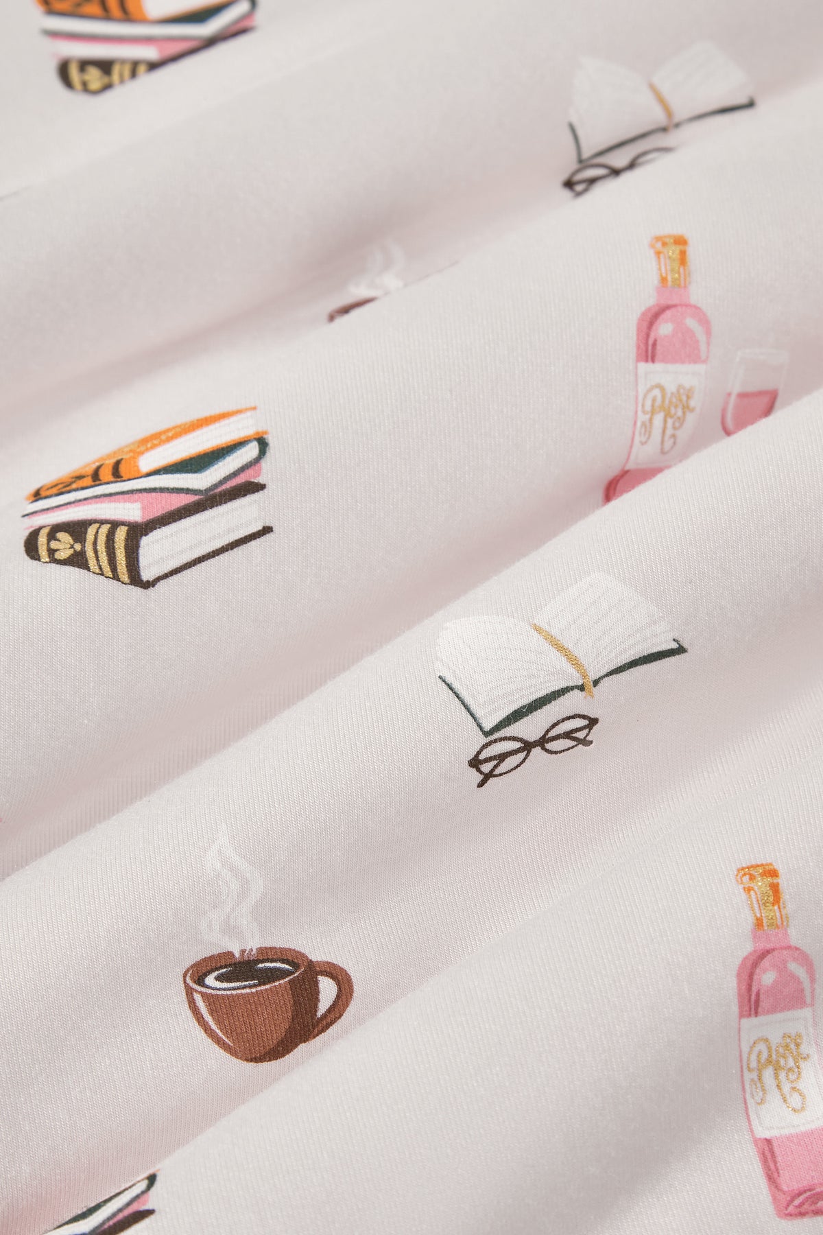 Close up of pink fabric with books with, specs and coffee cup print on it 
