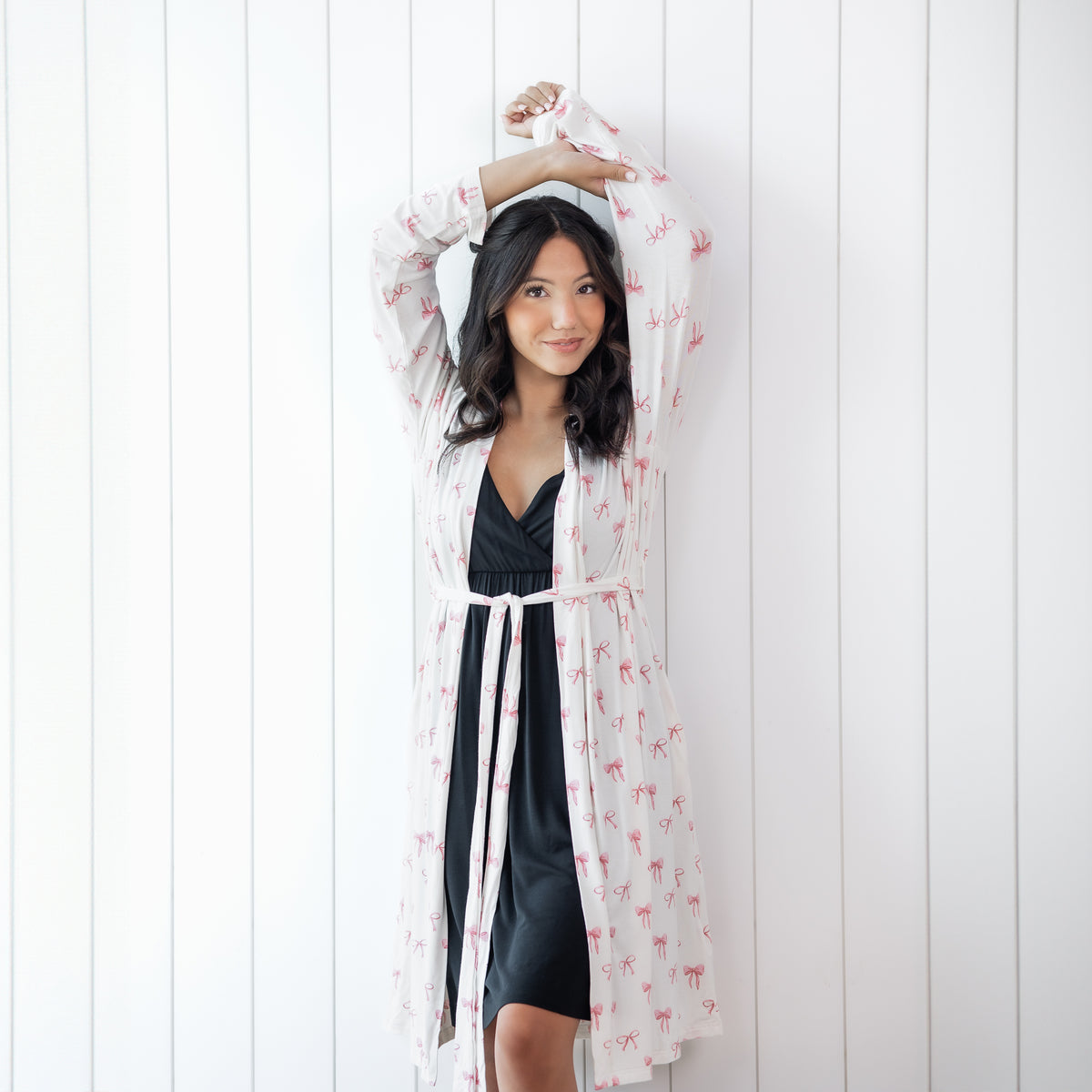 Woman in black nightgown and white robe with pink bow print 