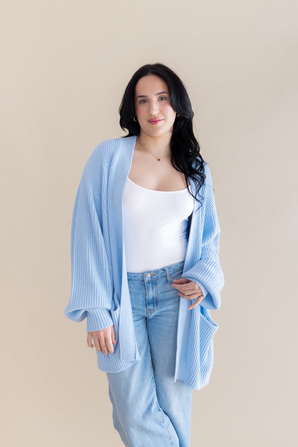 Female model posing wearing the Chunky Knit Women's Oversized Cardigan in Breeze over a white tank top and light wash jeans