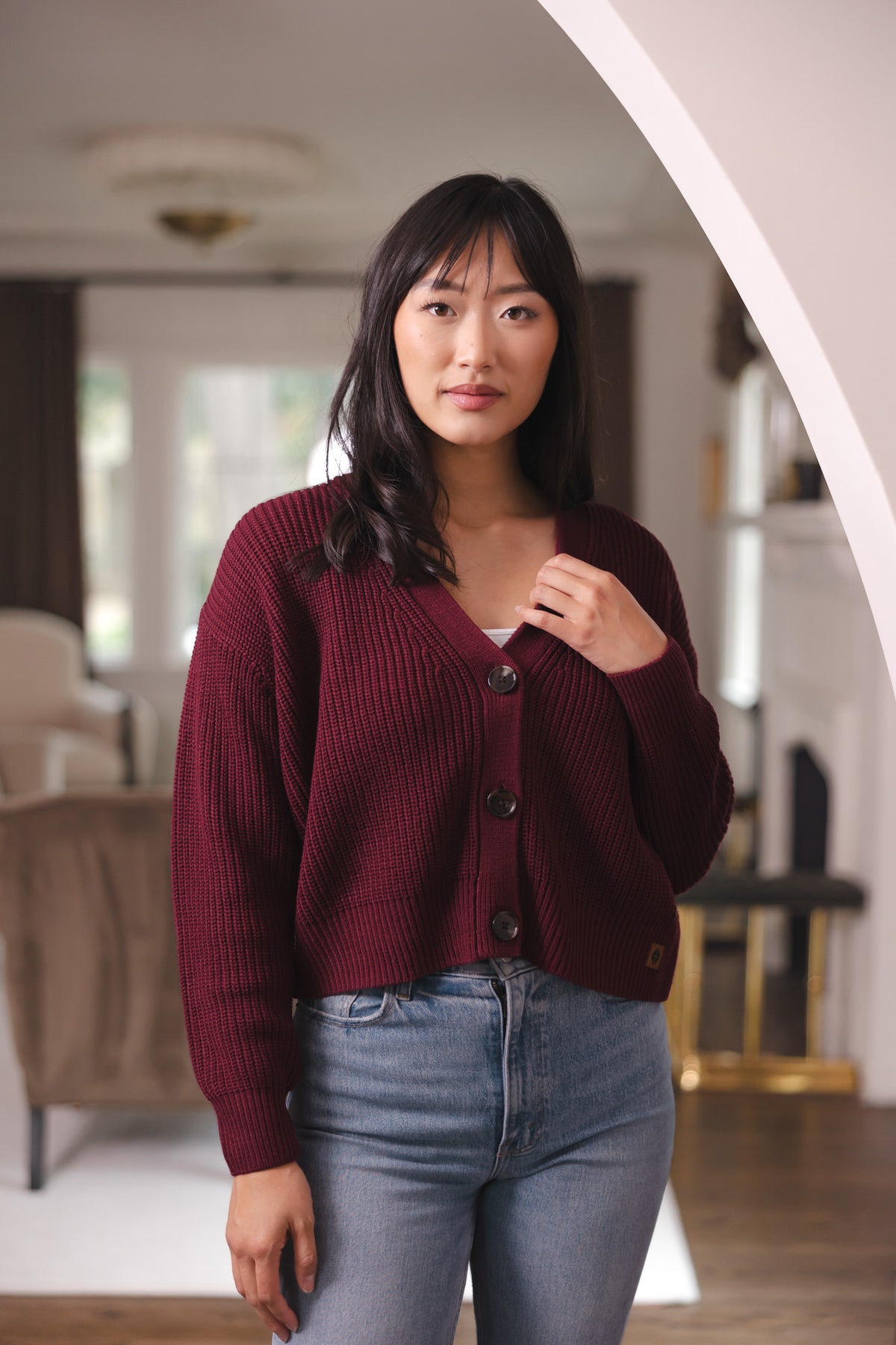 Modal posing in Chunky Knit Women's Cropped Cardigan in Burgundy over blue jeans