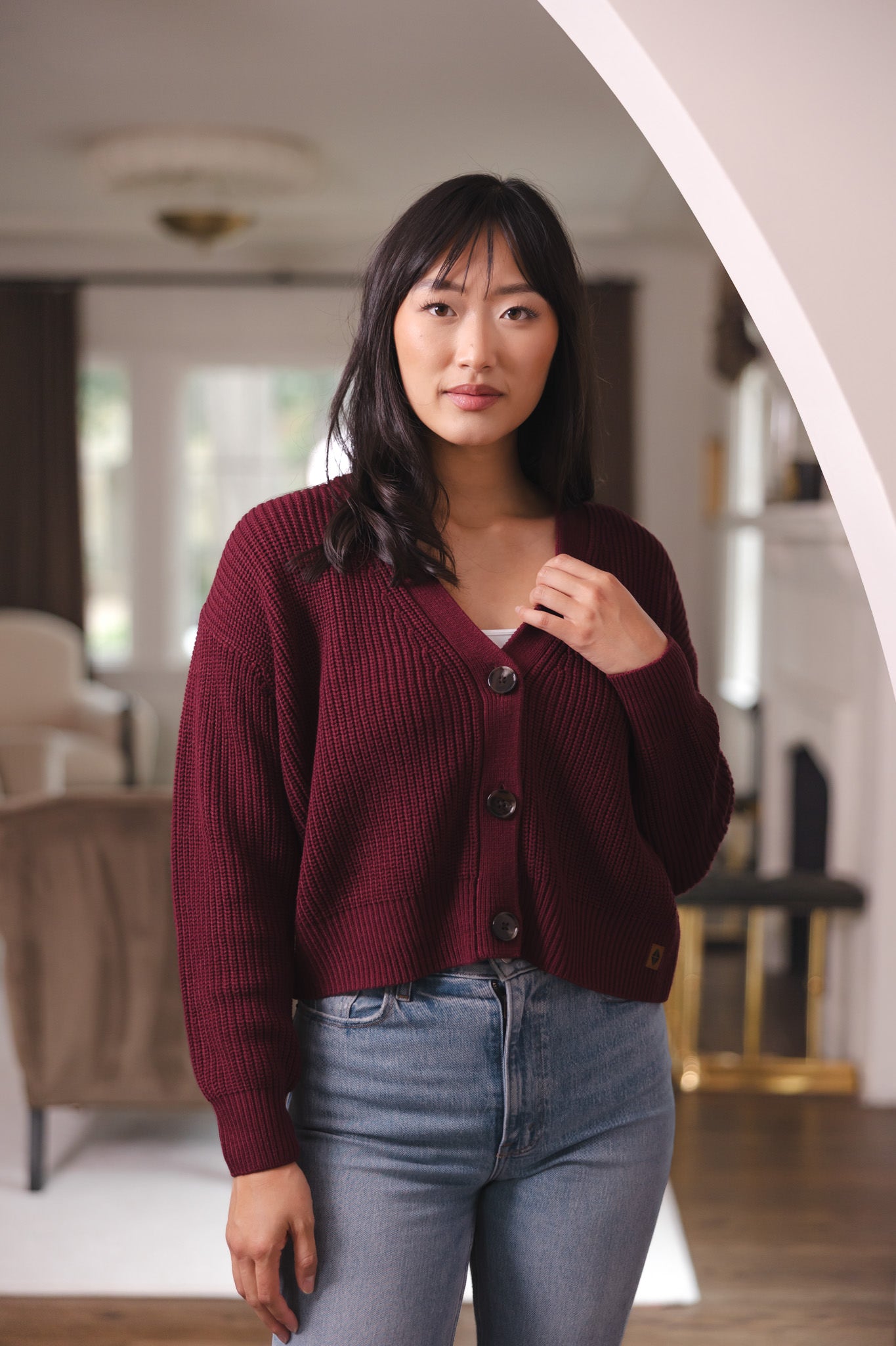 Modal posing in Chunky Knit Women's Cropped Cardigan in Burgundy over blue jeans