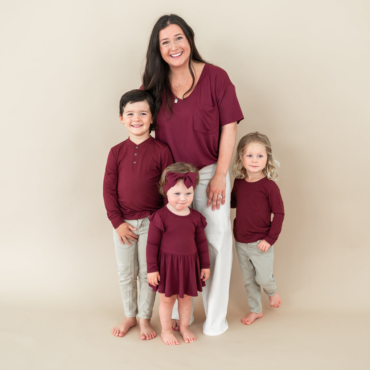 Family matching in Burgundy. Pictured are the women's v-neck, Long Sleeve Toddler Henley Tee, toddler long sleeve crew neck and the twirl bodysuit dress