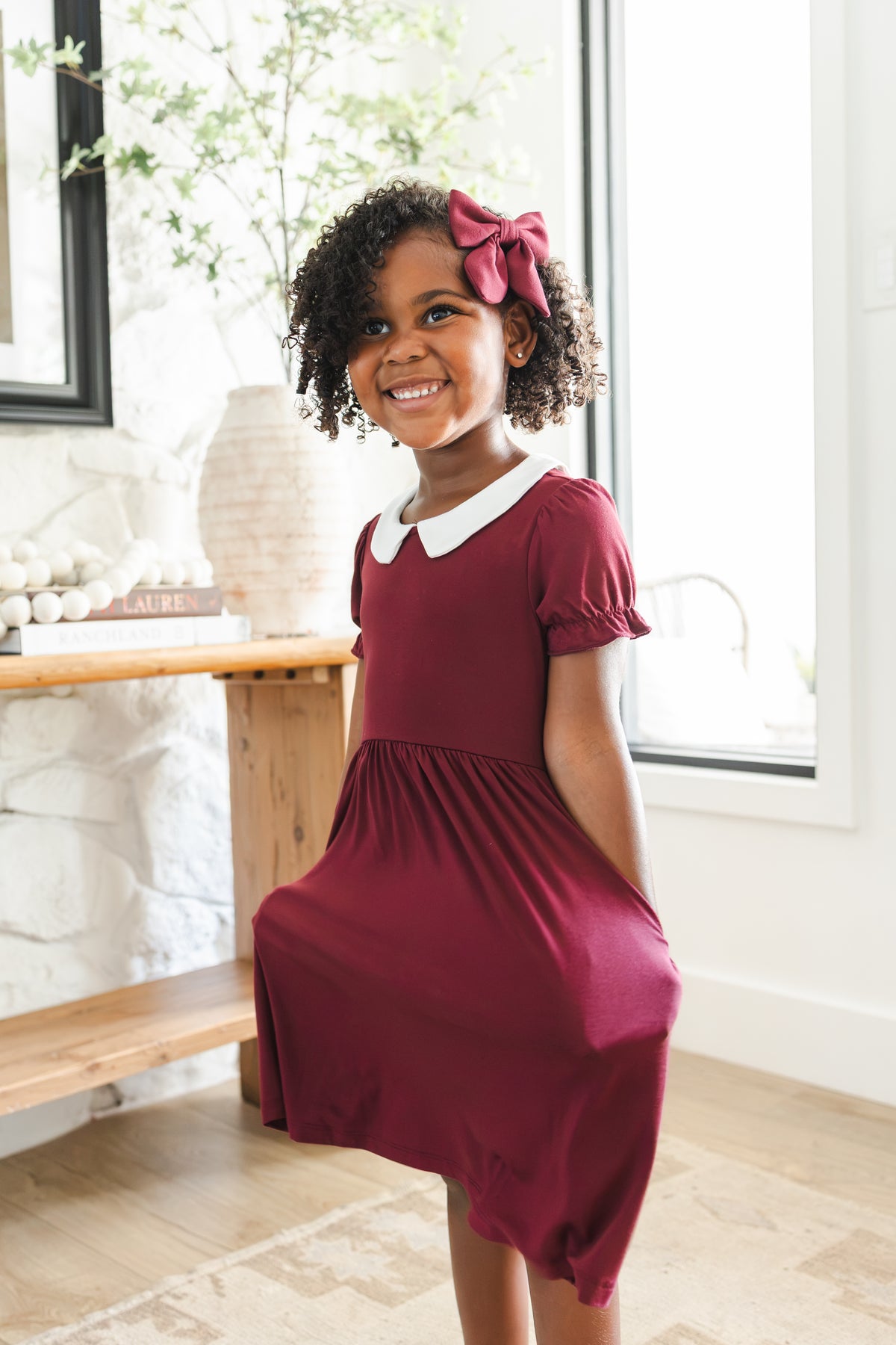 Girl posing in Peter Pan Collar Dress in Burgundy with Medium Alligator clip bow 