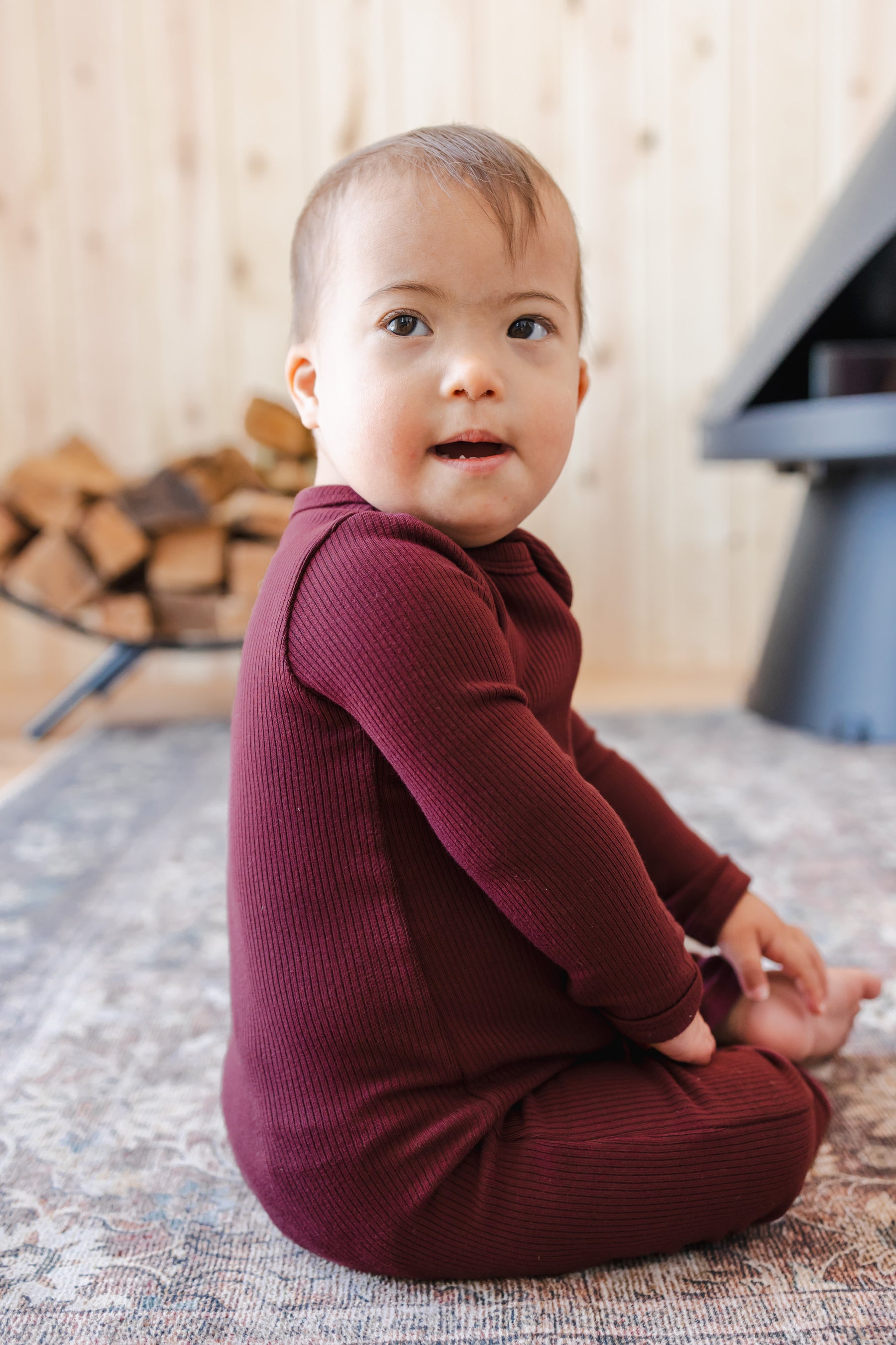 Toddler sitting on a carpet wearing Ribbed Zipper Romper in Burgundy