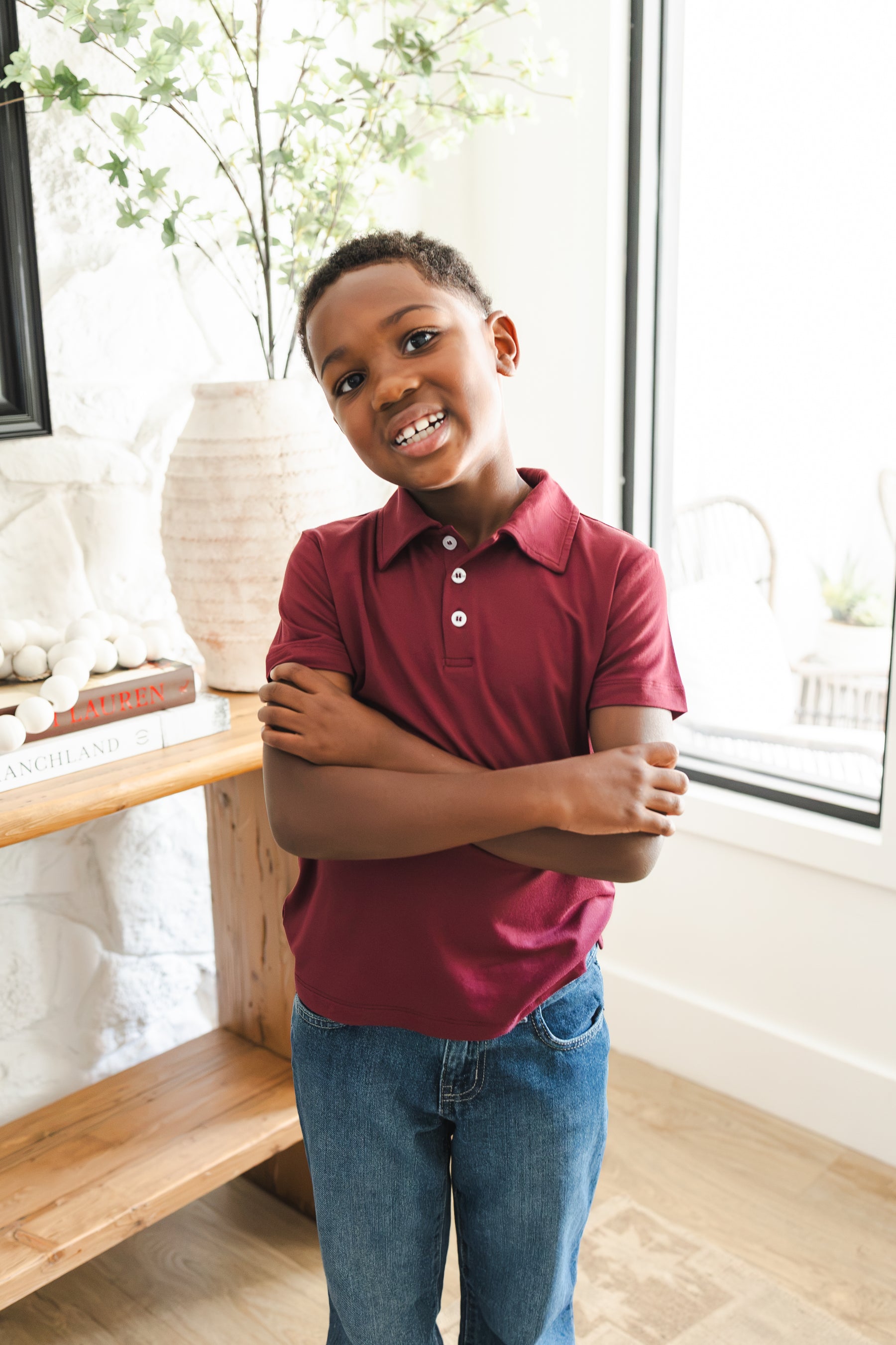 Boy wearing Toddler Short Sleeve Polo in Burgundy standing with folded hands on blue jeans