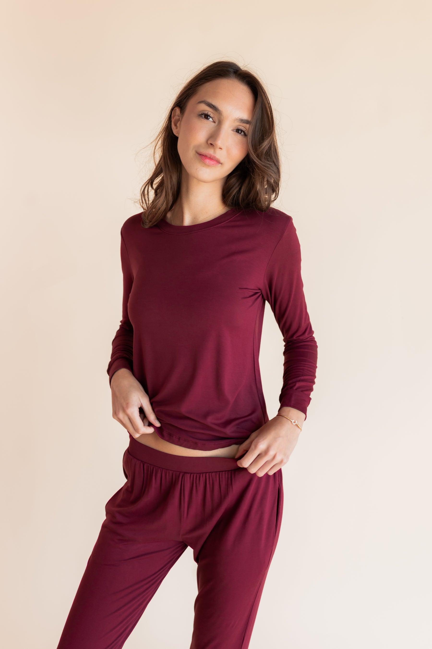 Model posing Women's Jogger Pajama Set in Burgundy on a beige background