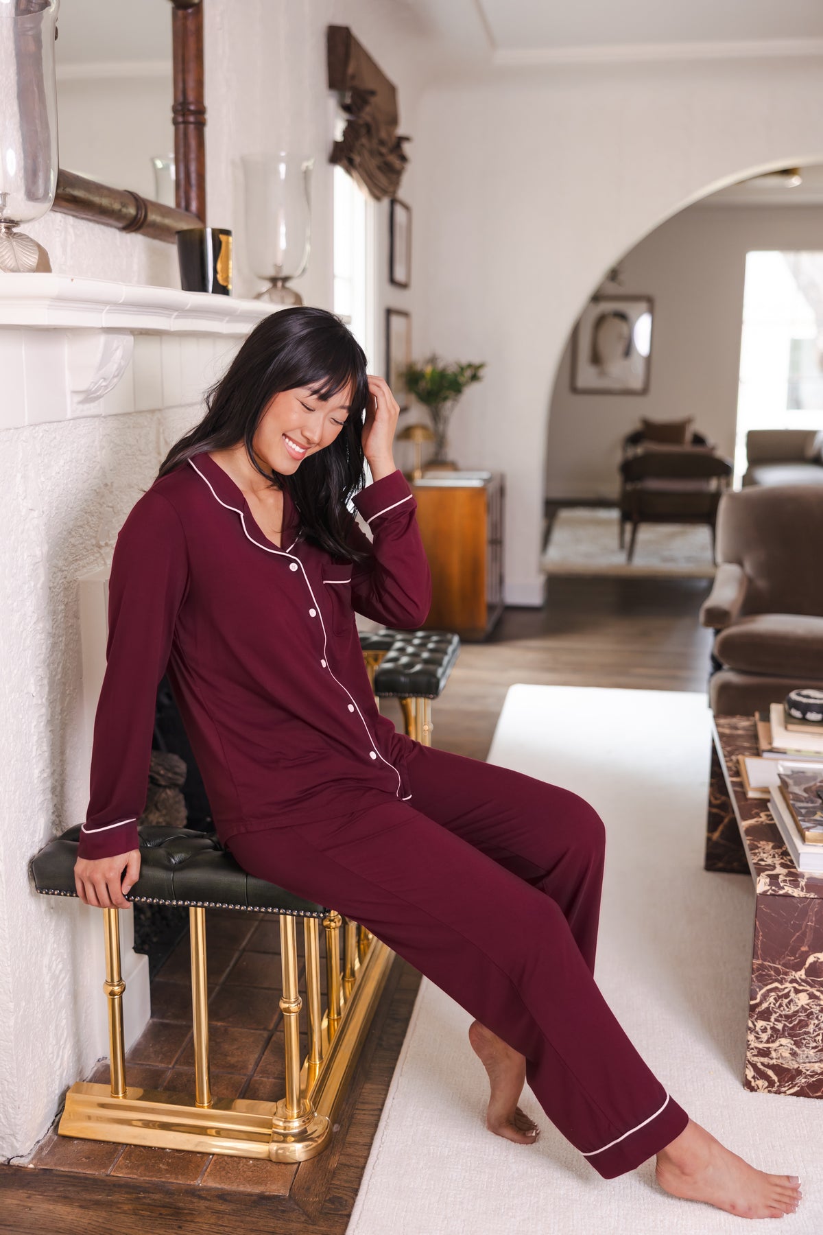 Modal wearing Long-Sleeved Women's Pajama Set in Burgundy with Burgundy Trim smiling sitting on a chair