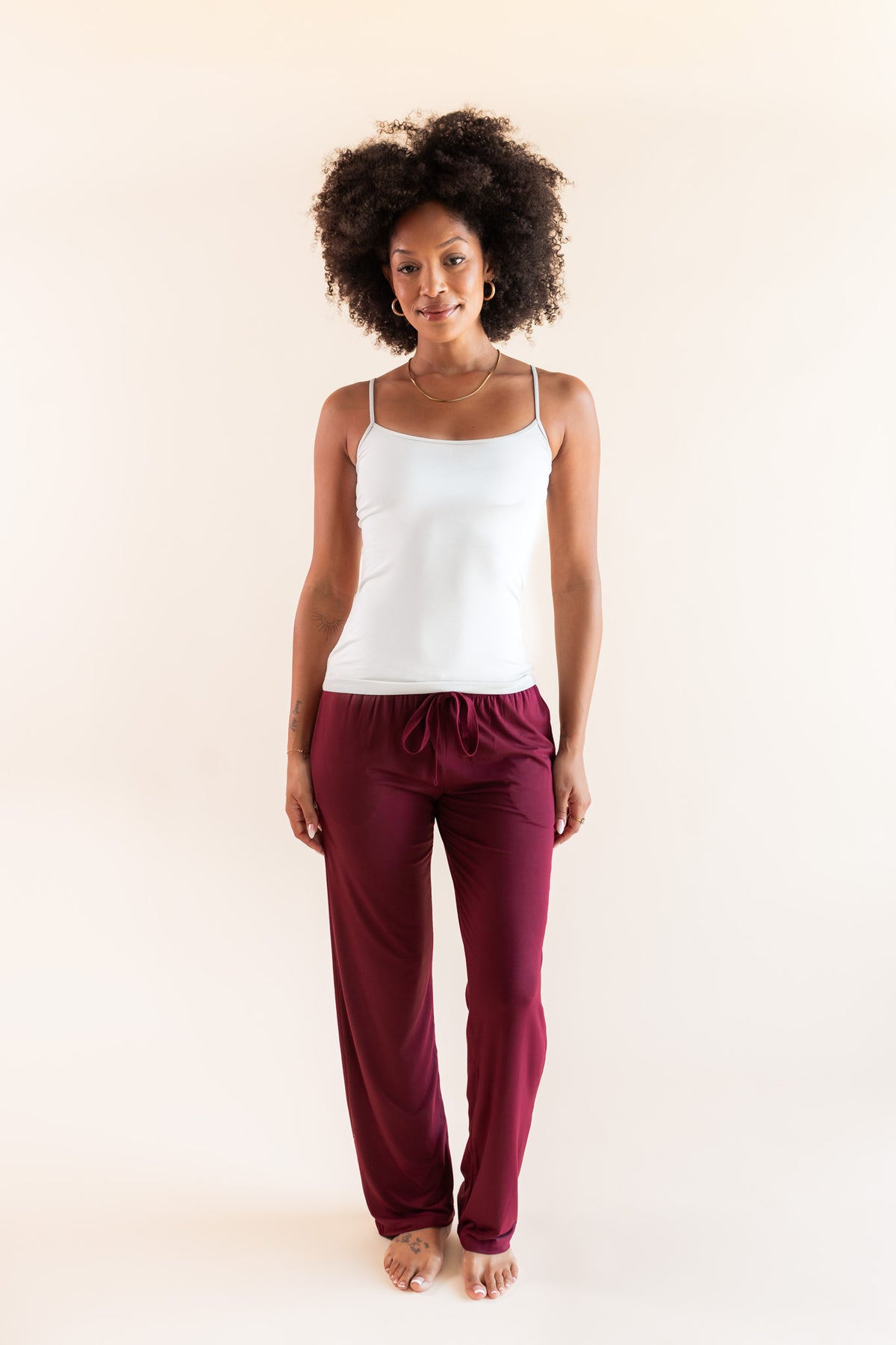 Modal posing in Women's Lounge Pants in Burgundy under white camisole on a beige background