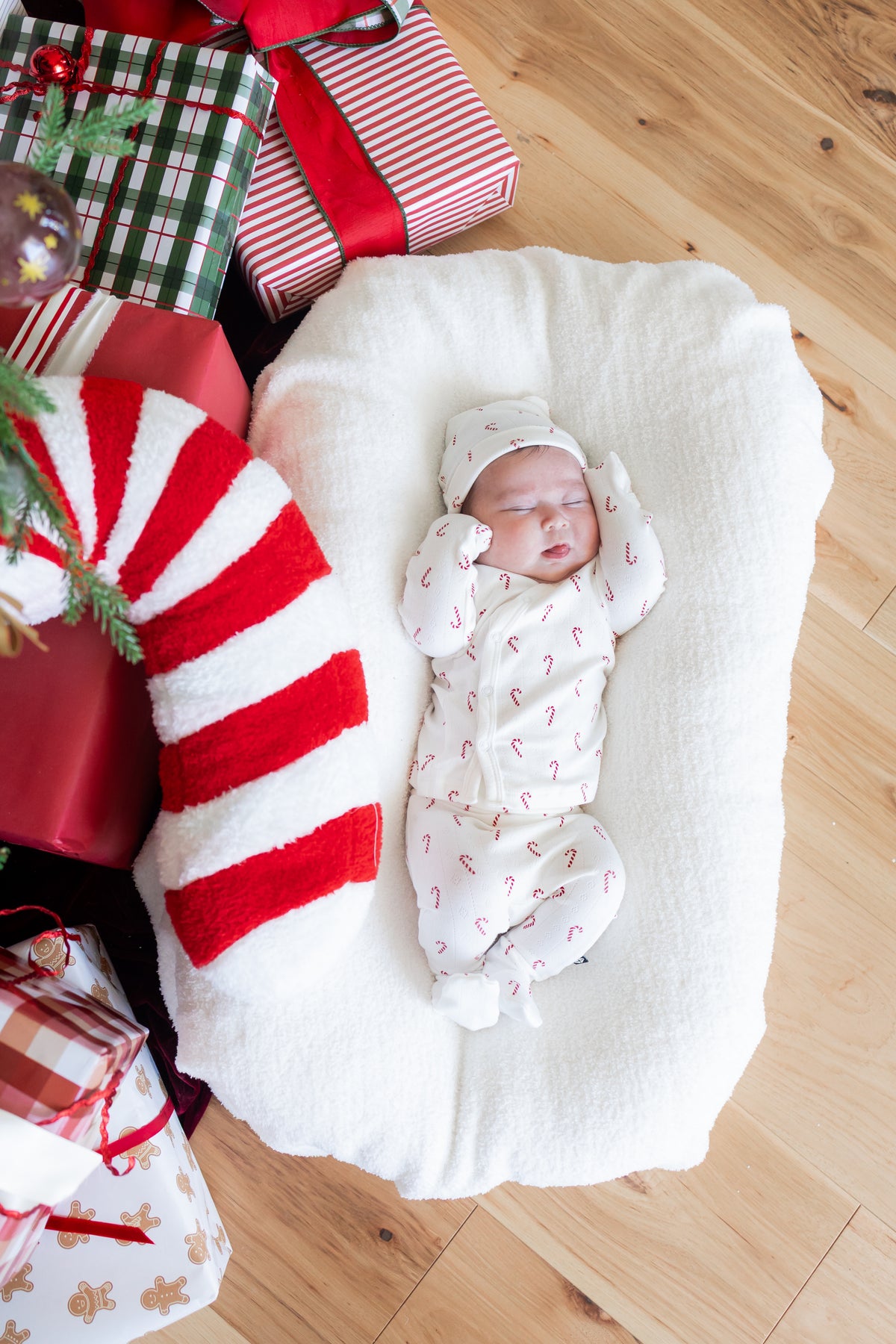 Baby sleeping wearing Pointelle Take Me Home Set with Cap in Candy Cane print on a white crib sheet