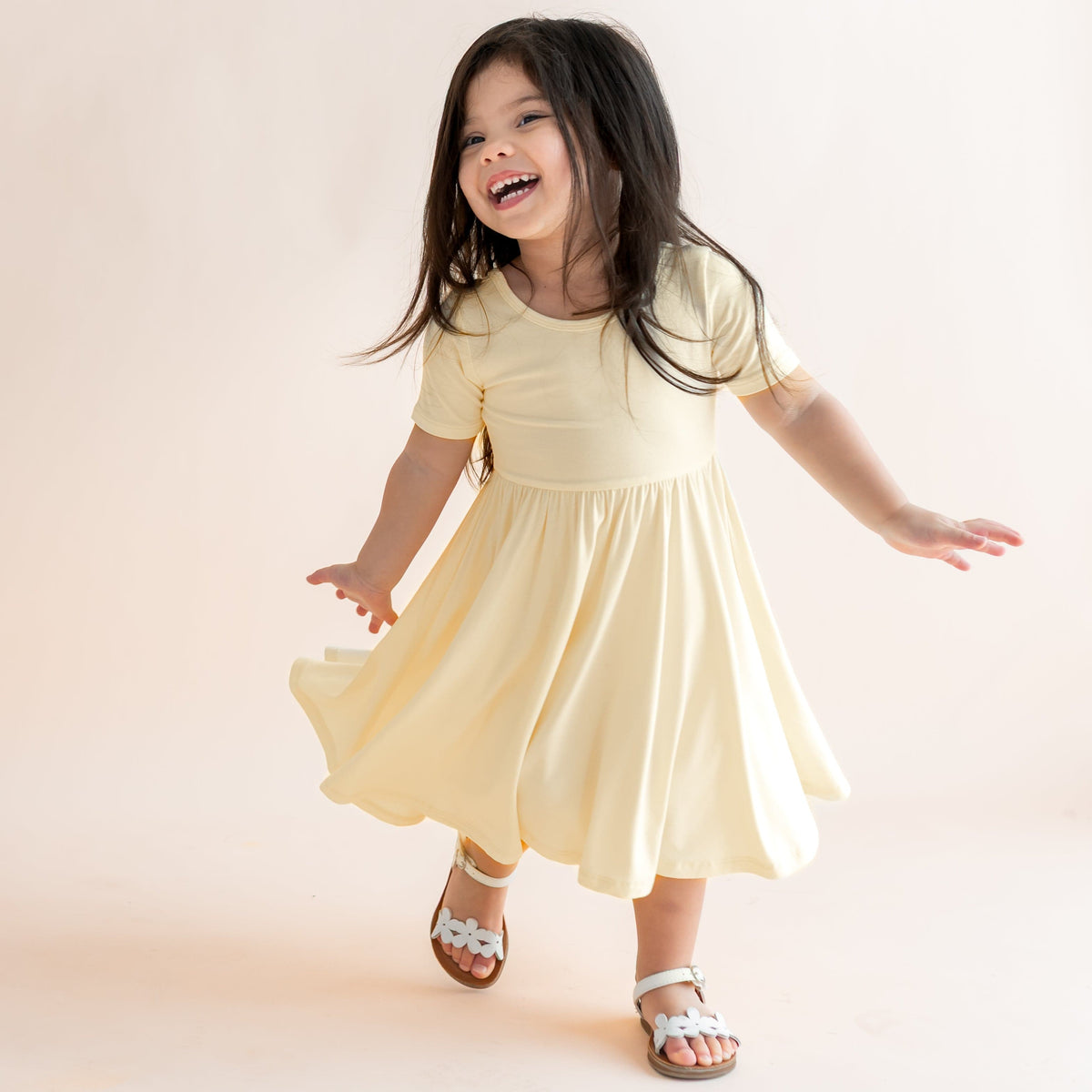 Child in a yellow dress standing on a light background