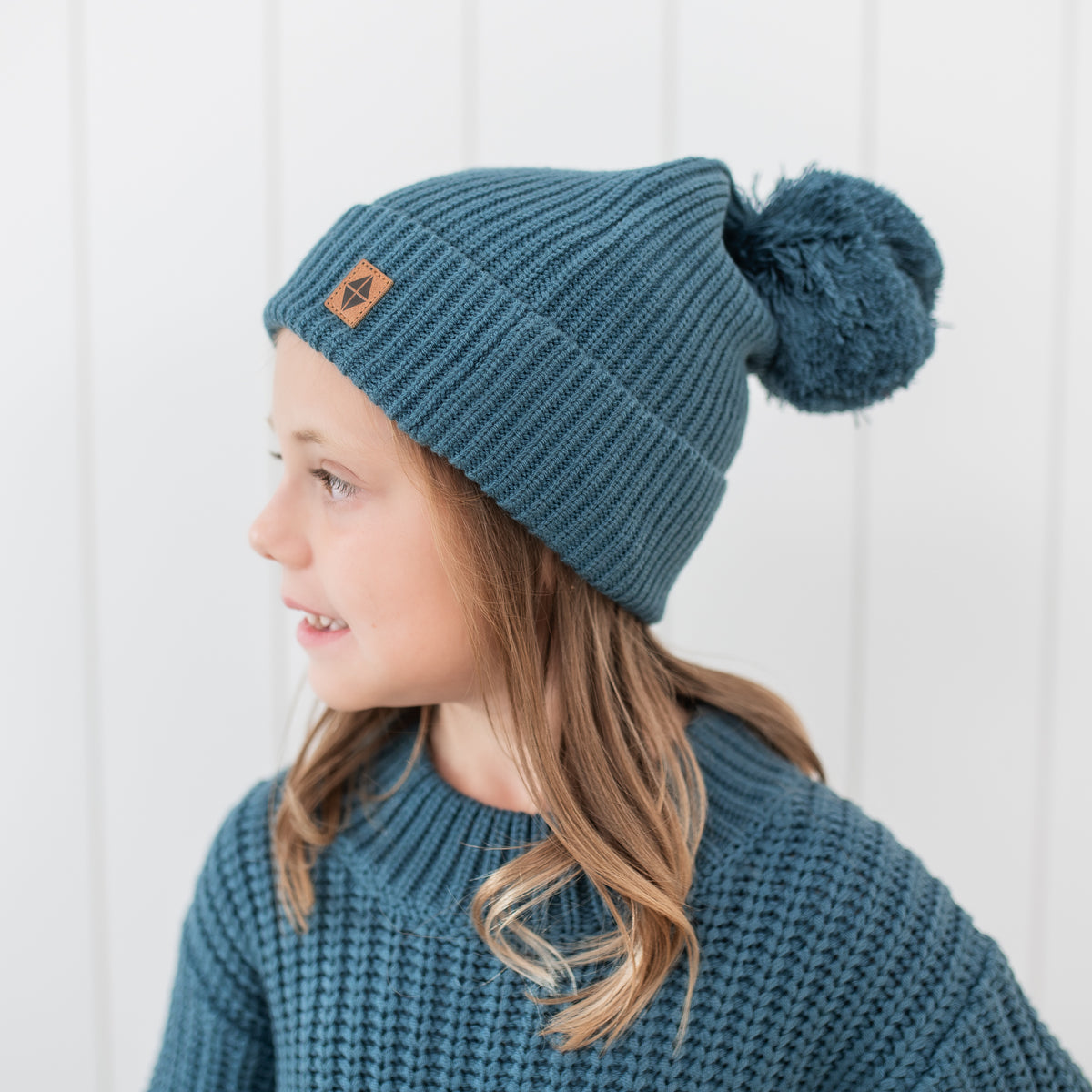 Close up of the Chunky Knit Pom Beanie in Atlantic shown on a girl model 
