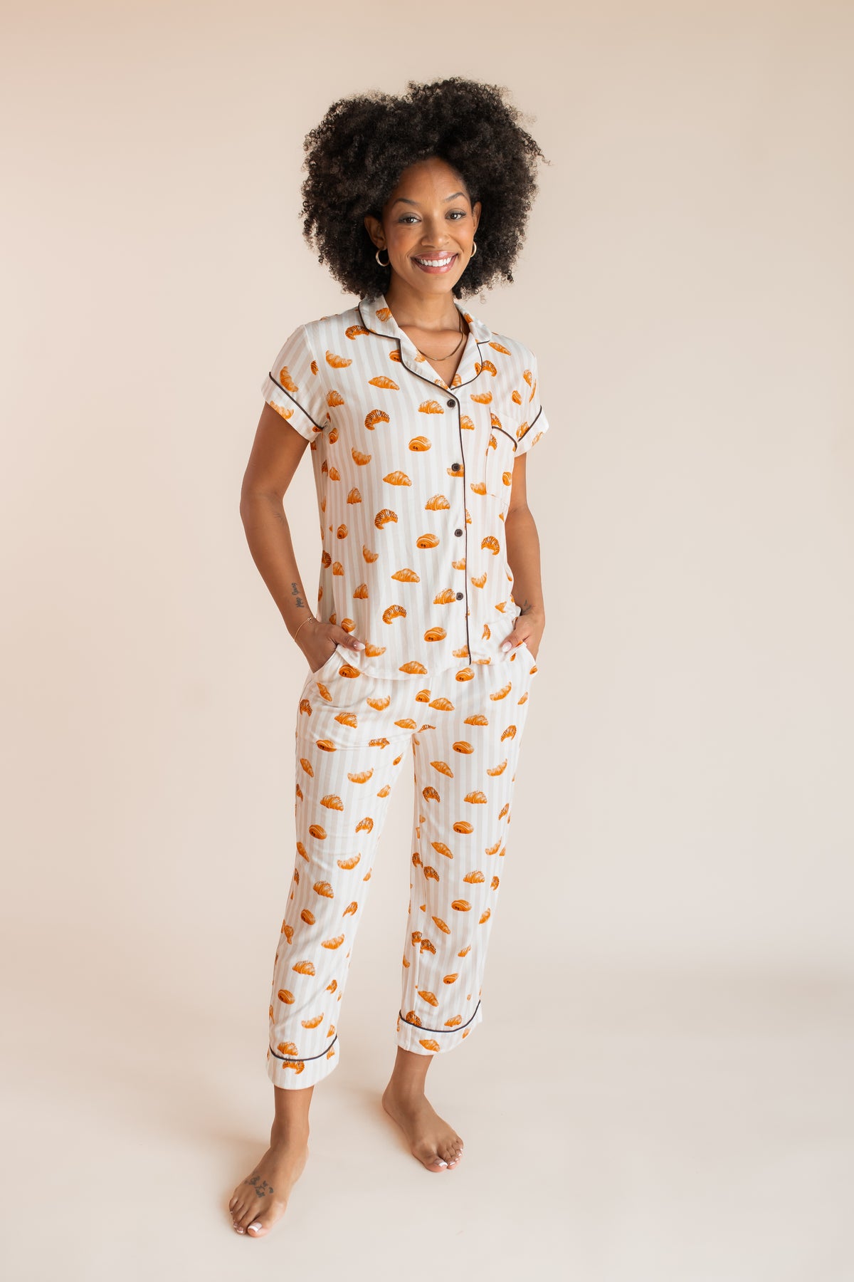 Model posing in Women's Short Sleeve Cropped Pajama Set with Croissant print on a beige background