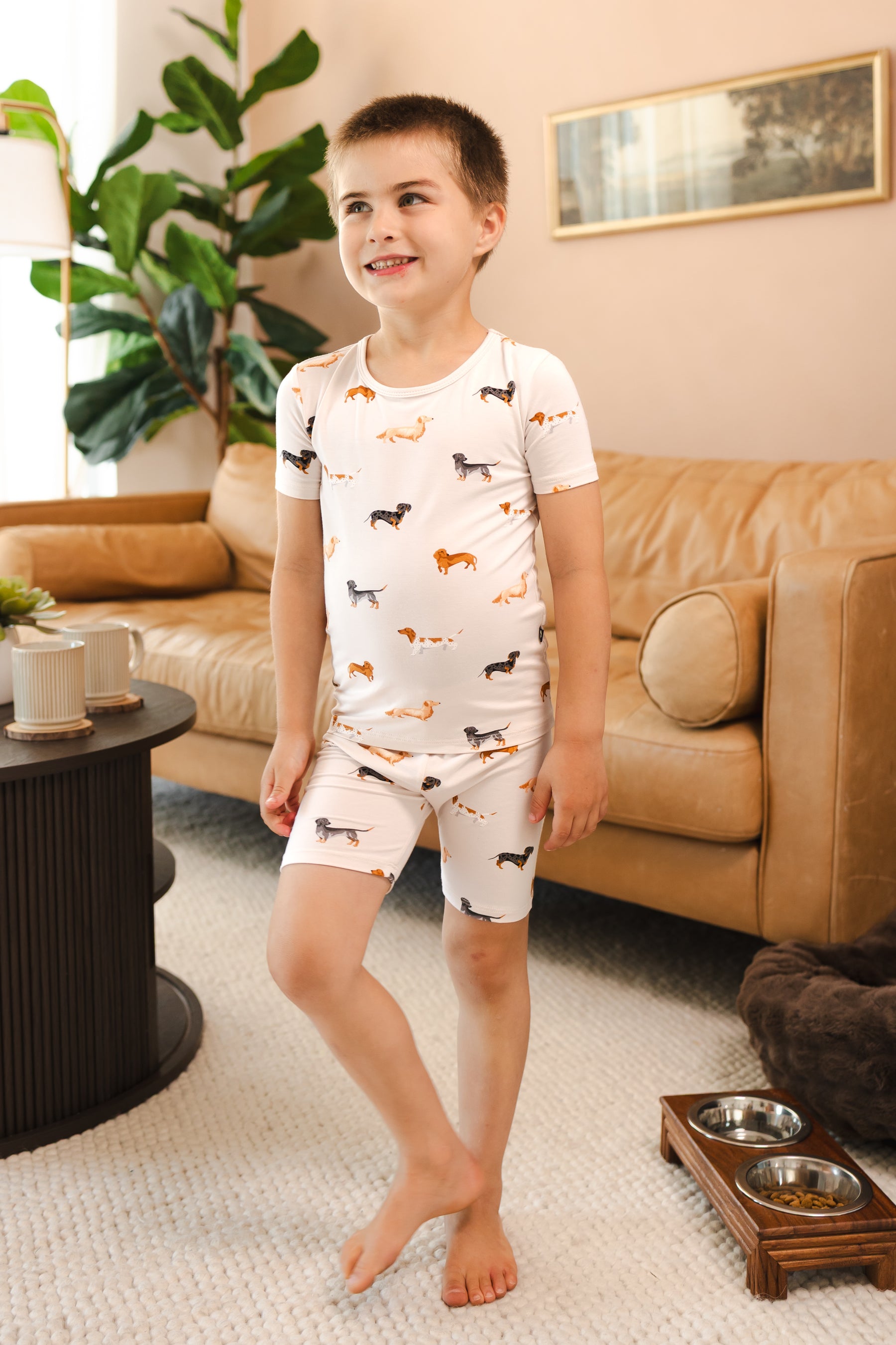 Boy wearing Beige Short Sleeve Pajamas in Dachshund print in a living room 