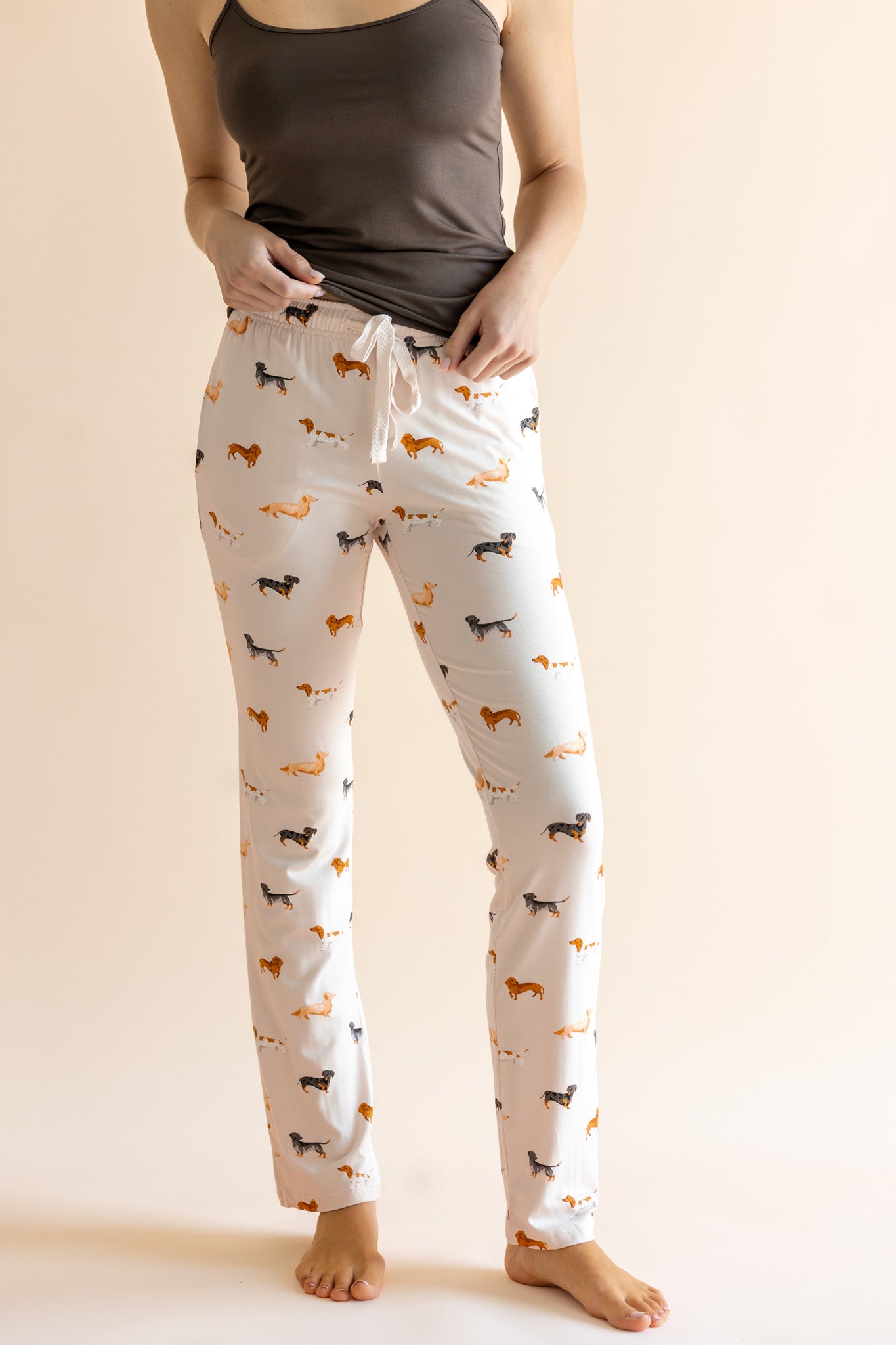 Model showing the drawstring of Women's Lounge Pants in Dachshund print under a brown camisole on a beige background