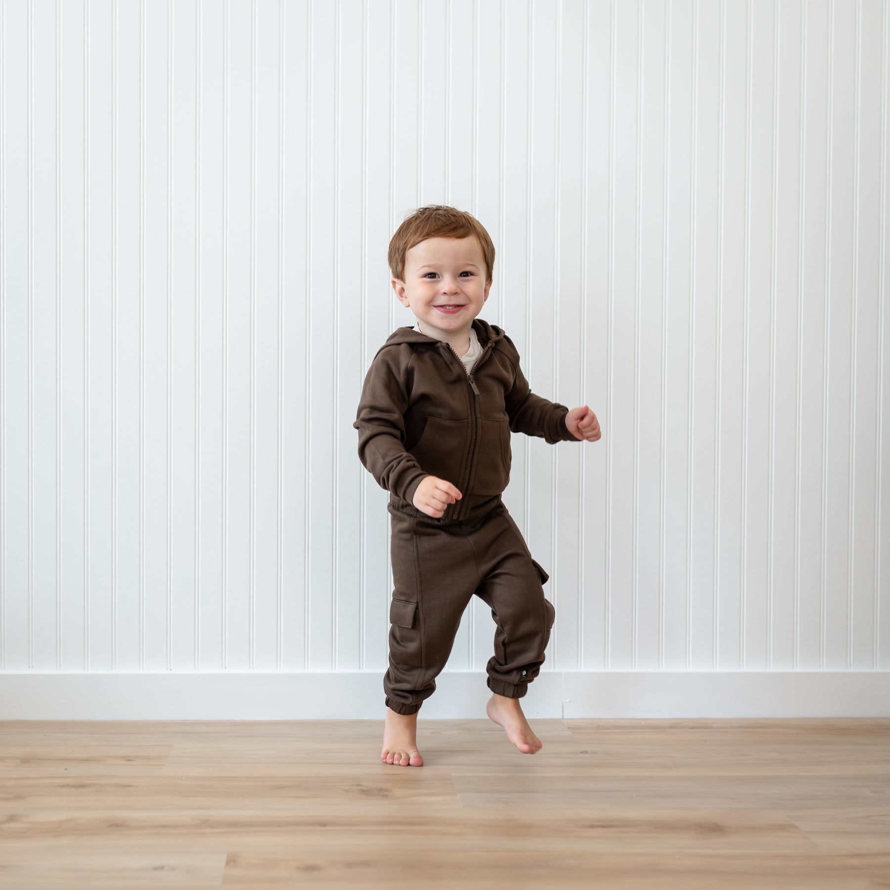 Young boy walking around wearing the Fleece Cargo Pants in Espresso and matching fleece zip hoodie