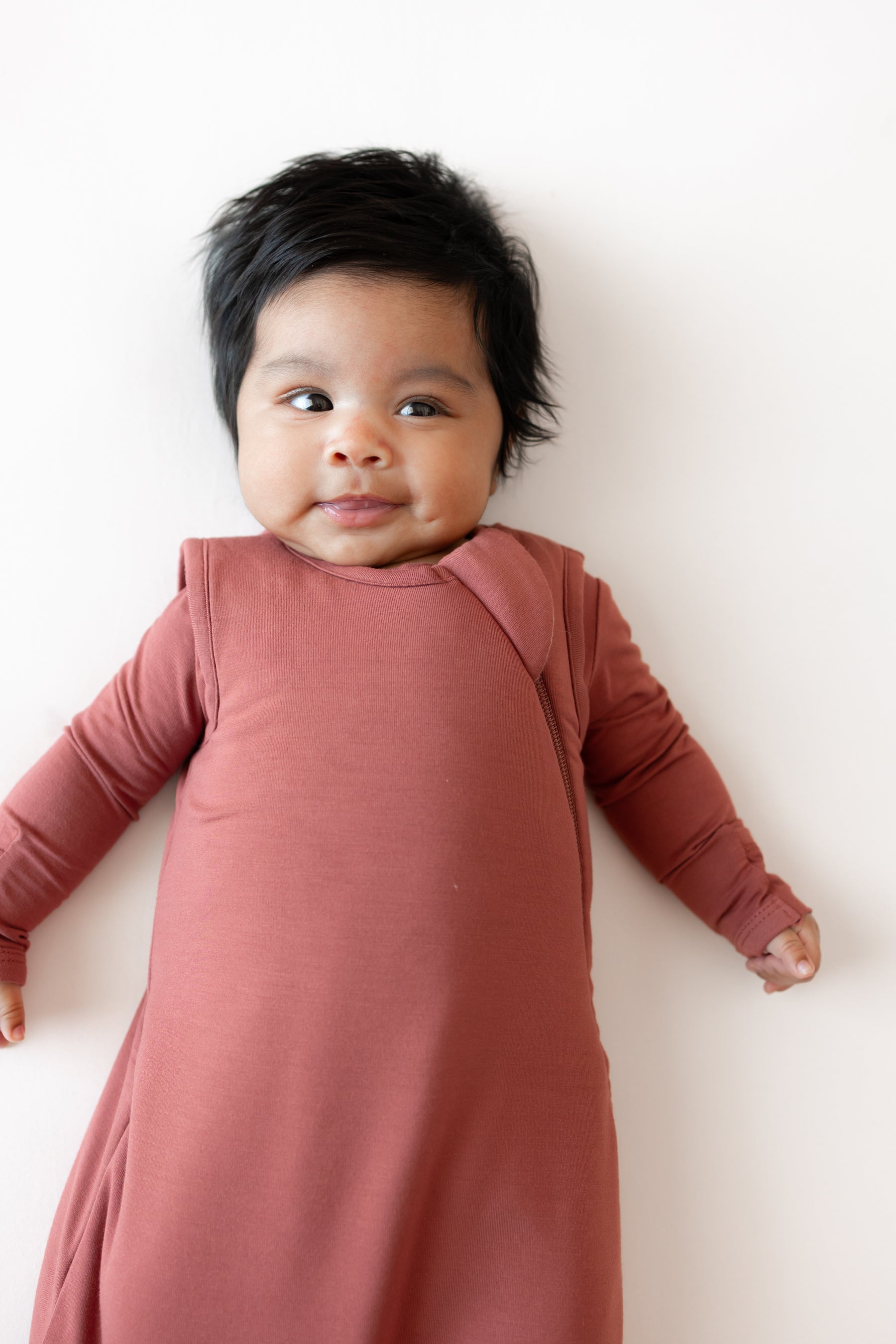 Close up of Baby smiling in Sleep Bag in Ember 1.0 on a white background