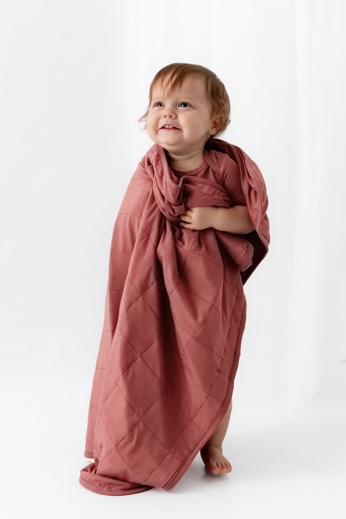 Baby wrapped in Baby Blanket in Ember on a white background
