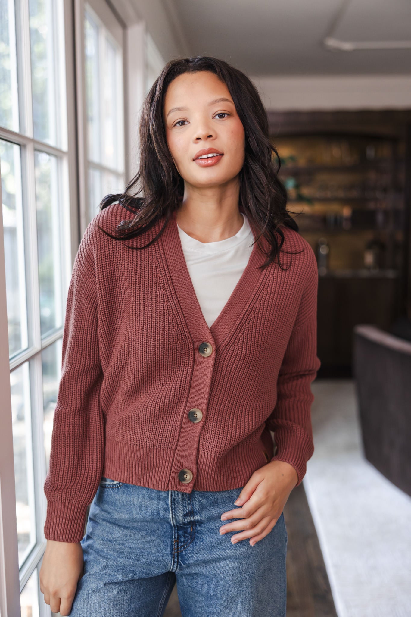 Modal wearing Chunky Knit Women's Cropped Cardigan In Ember over white T-shirt and blue jeans