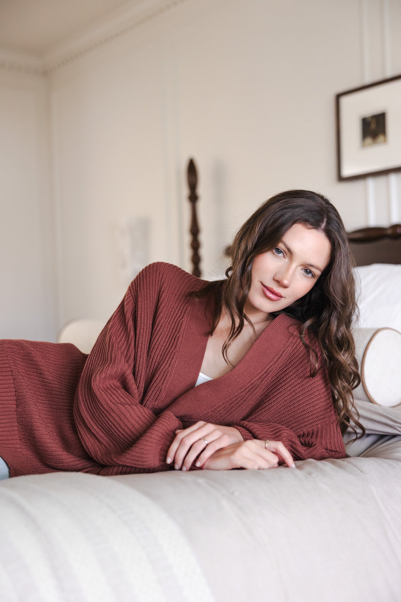 Modal lying on bed wearing Chunky knit oversized cardigan in ember over white t-shirt
