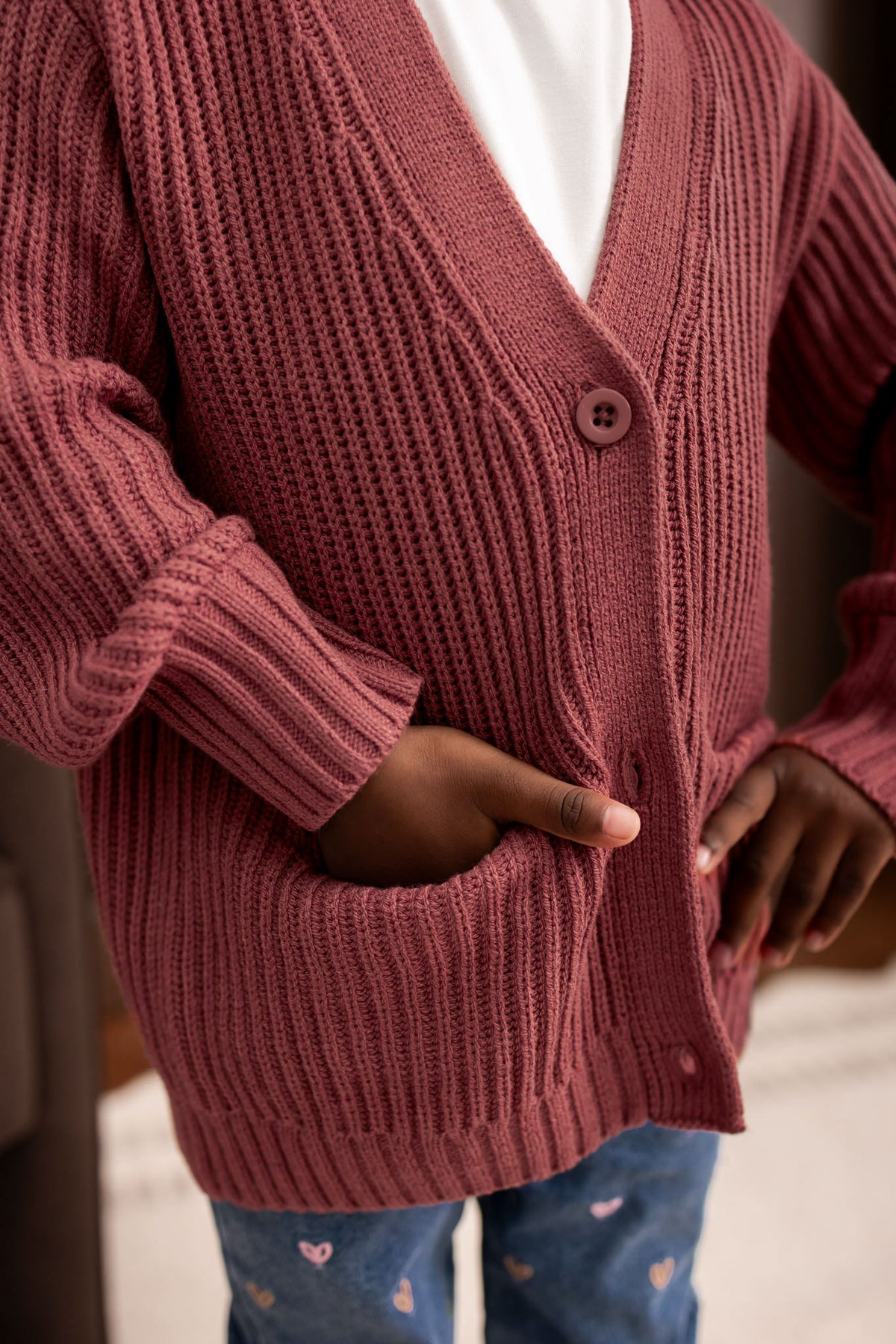 Child wearing Chunky Knit Oversized Cardigan in Ember over White T-shirt and blue jeans
