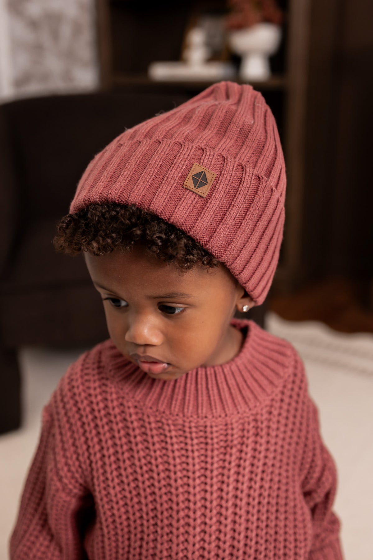 Boy wearing Chunky Knit Ribbed Beanie and chunky knit sweater in Ember in a living room