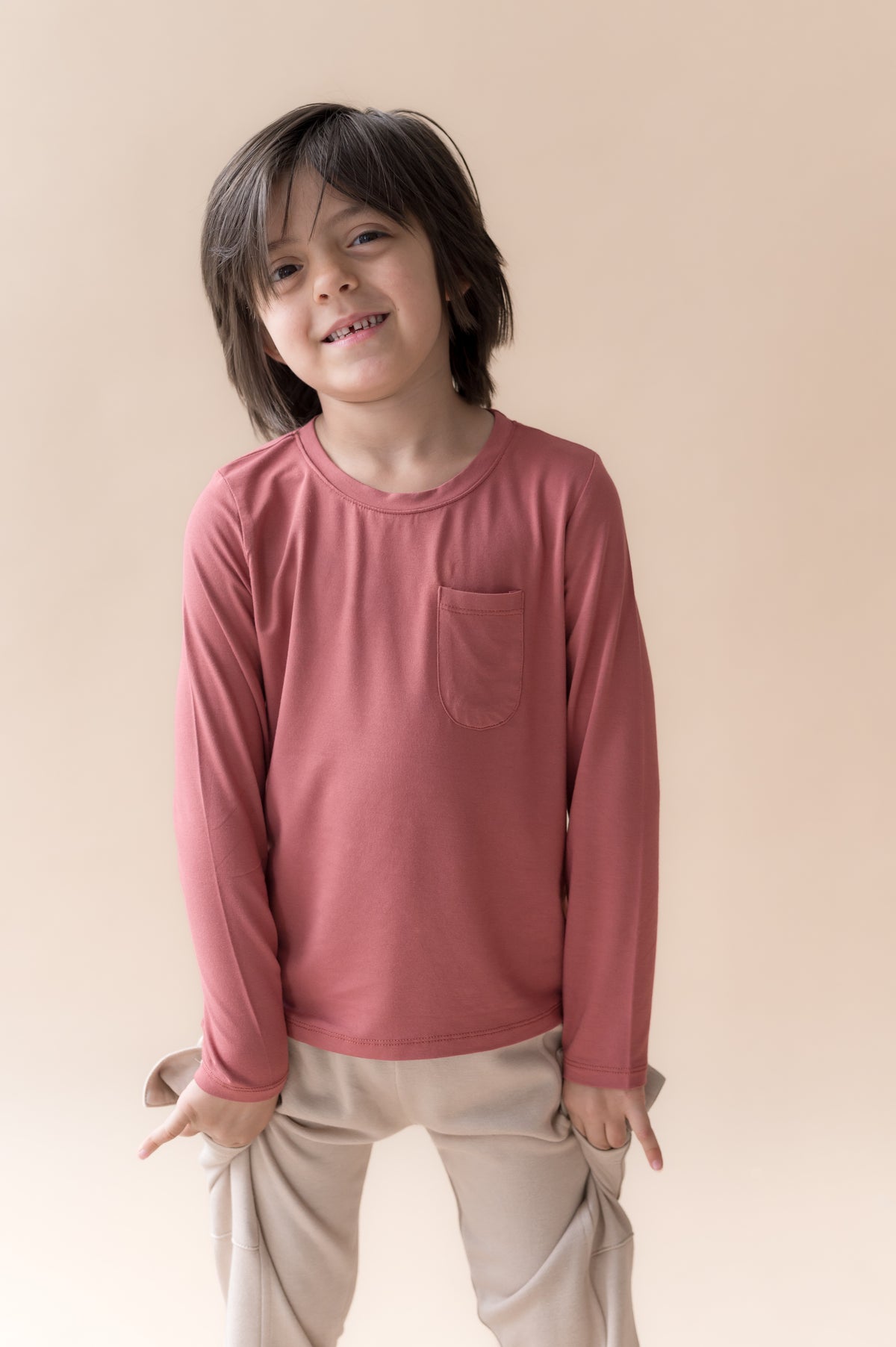 Boy wearing Long Sleeve Toddler Crew Neck Tee in Ember over a beige pants