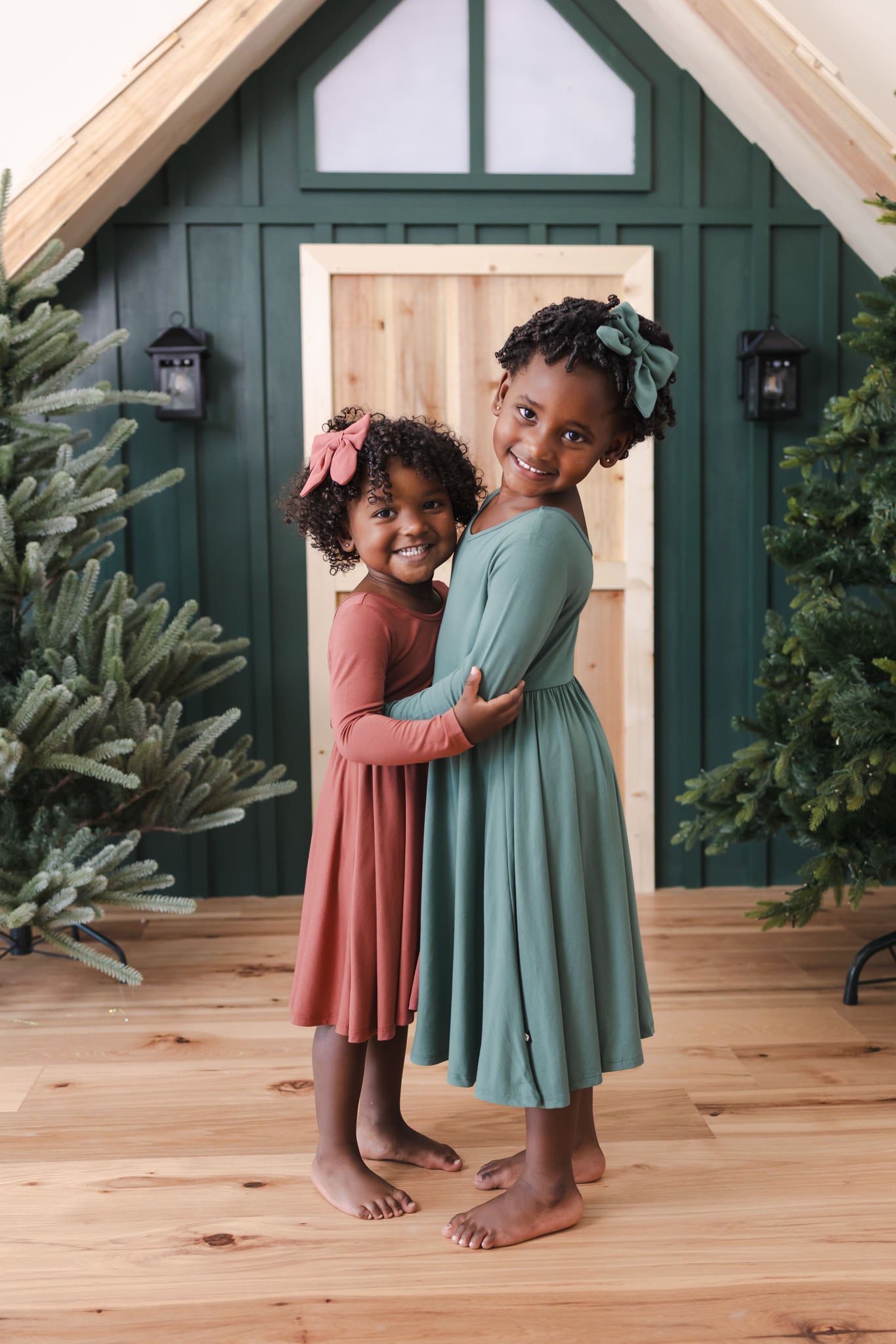 two girls hugging in long sleeve twirl bodysuit dress in colors ember and pine.