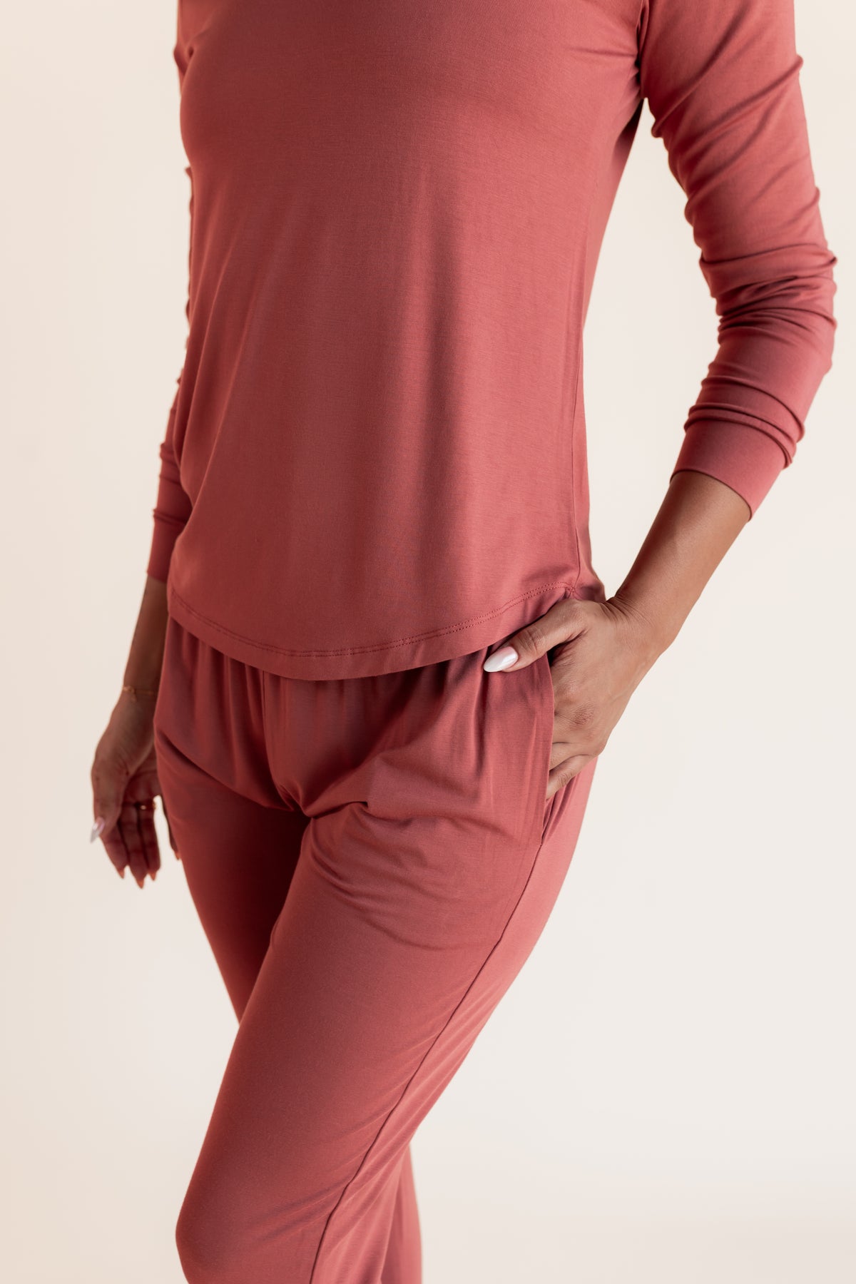 Model showing pockets on Women's Jogger Pajama Set in Ember on a beige background