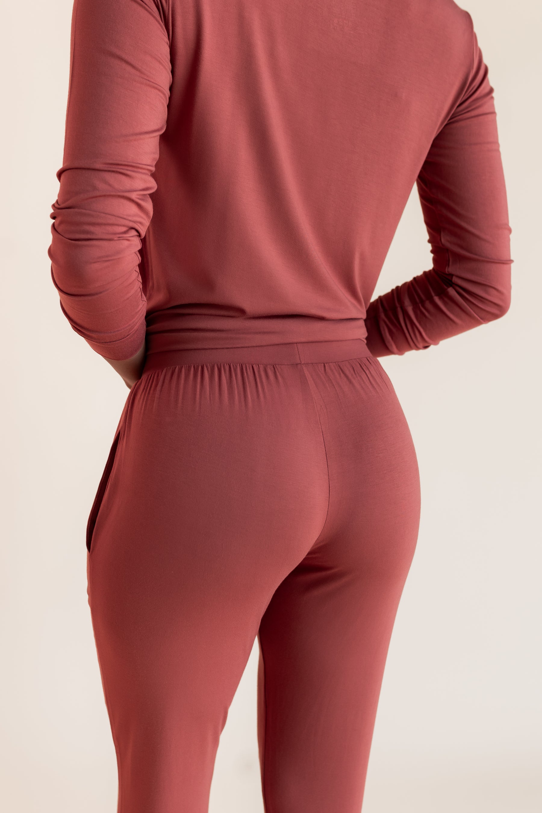 Model showing back side of Women's Jogger Pajama Set in Ember on a beige background