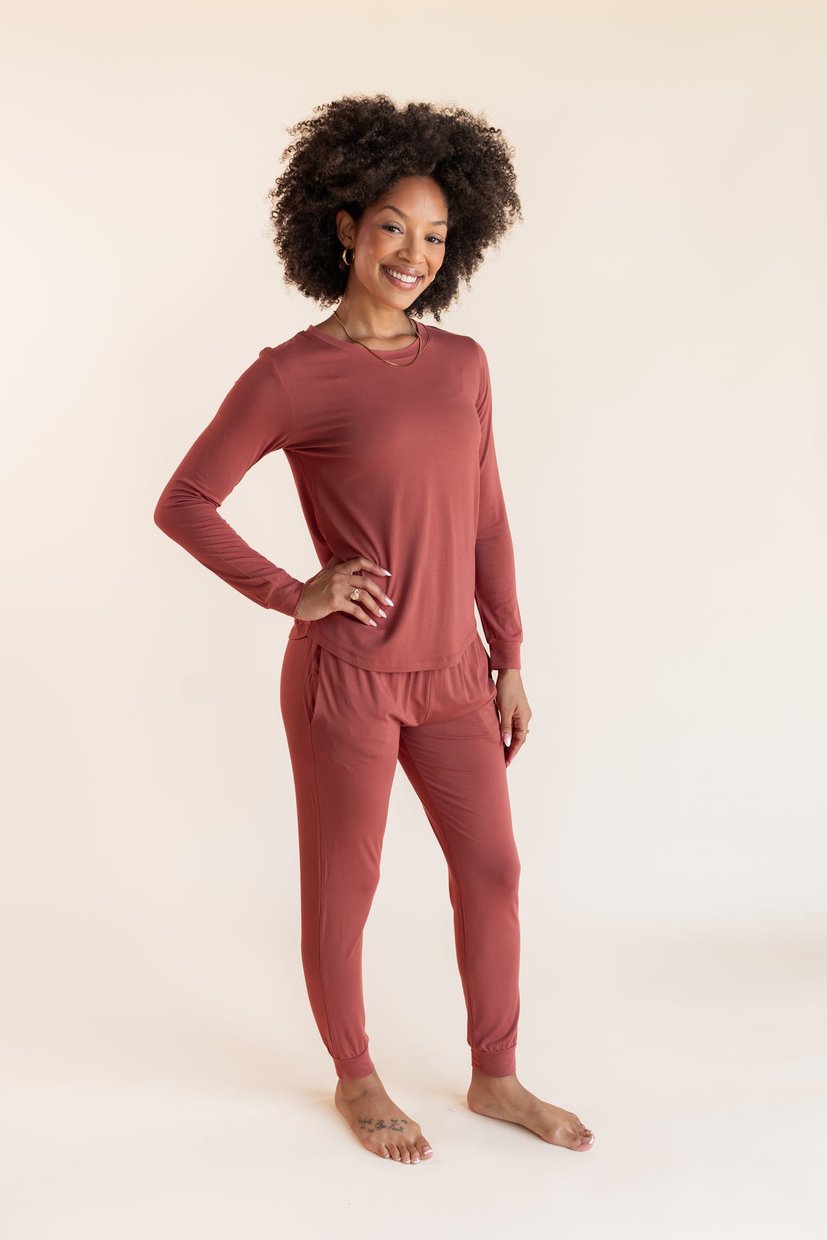 Model posing in Women's Jogger Pajama Set in Ember on a beige background