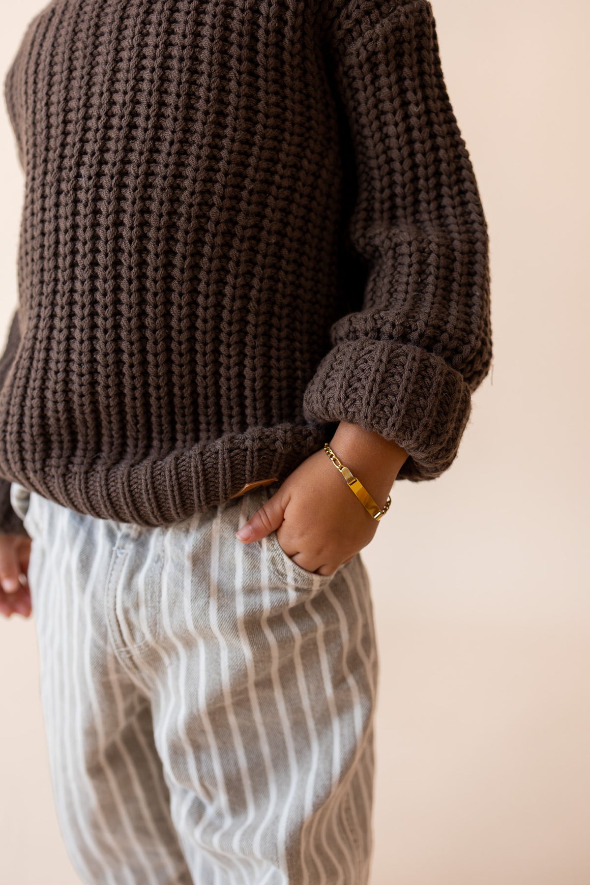 Close up of Boy wearing Chunky Knit Sweater in espresso over pants on a beige background