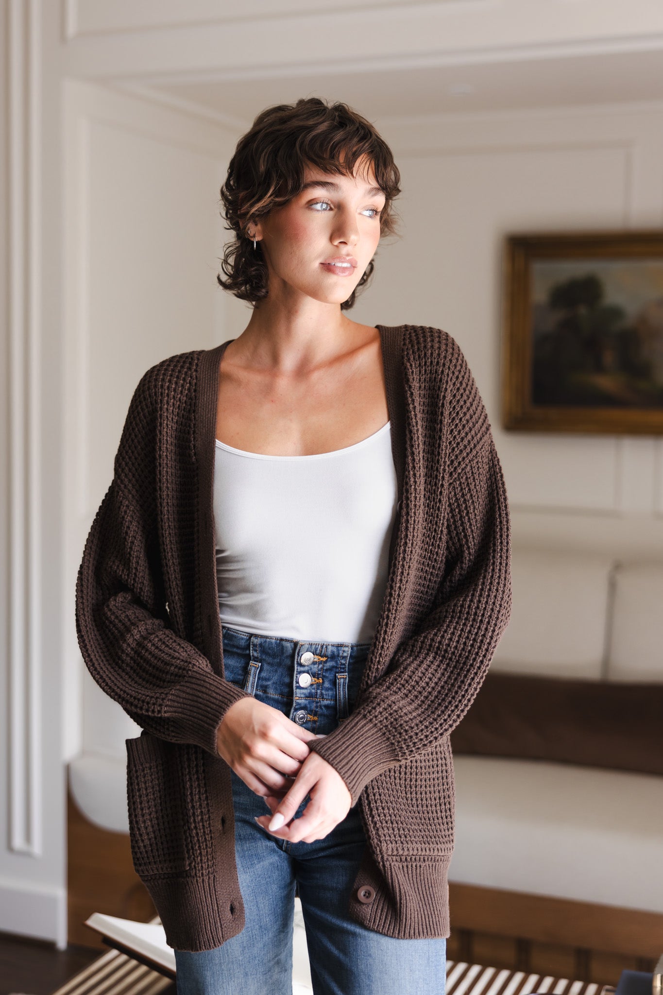 Modal posing in Chunky Knit Women's Waffle Cardigan in Espresso over white camisole and blue jeans
