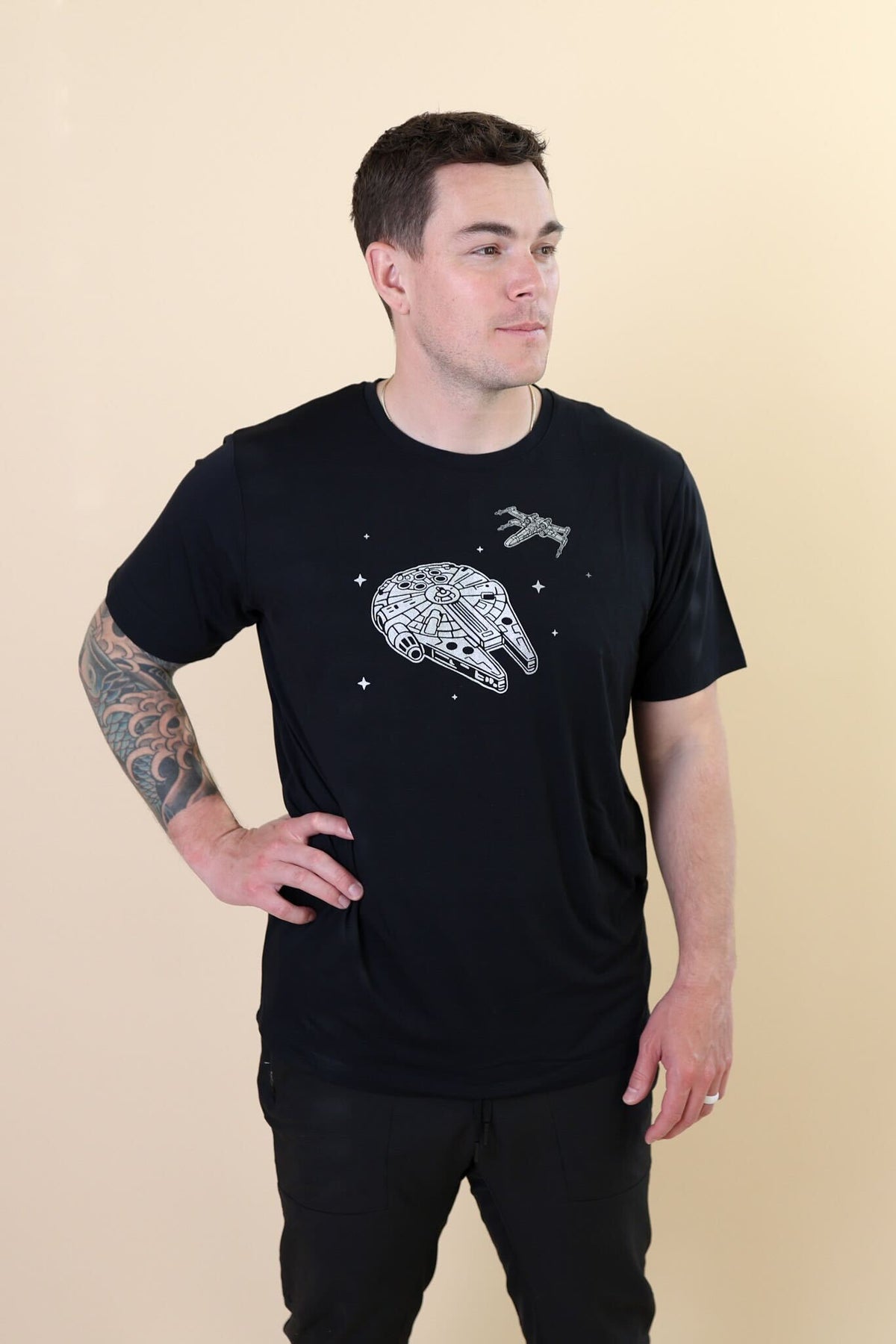 Male standing with one hand on his hip wearing the Men's Crew Neck Tee in Millennium Falcon™