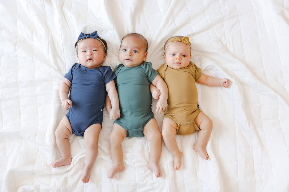 Three babies laying down with short sleeve bodysuits on