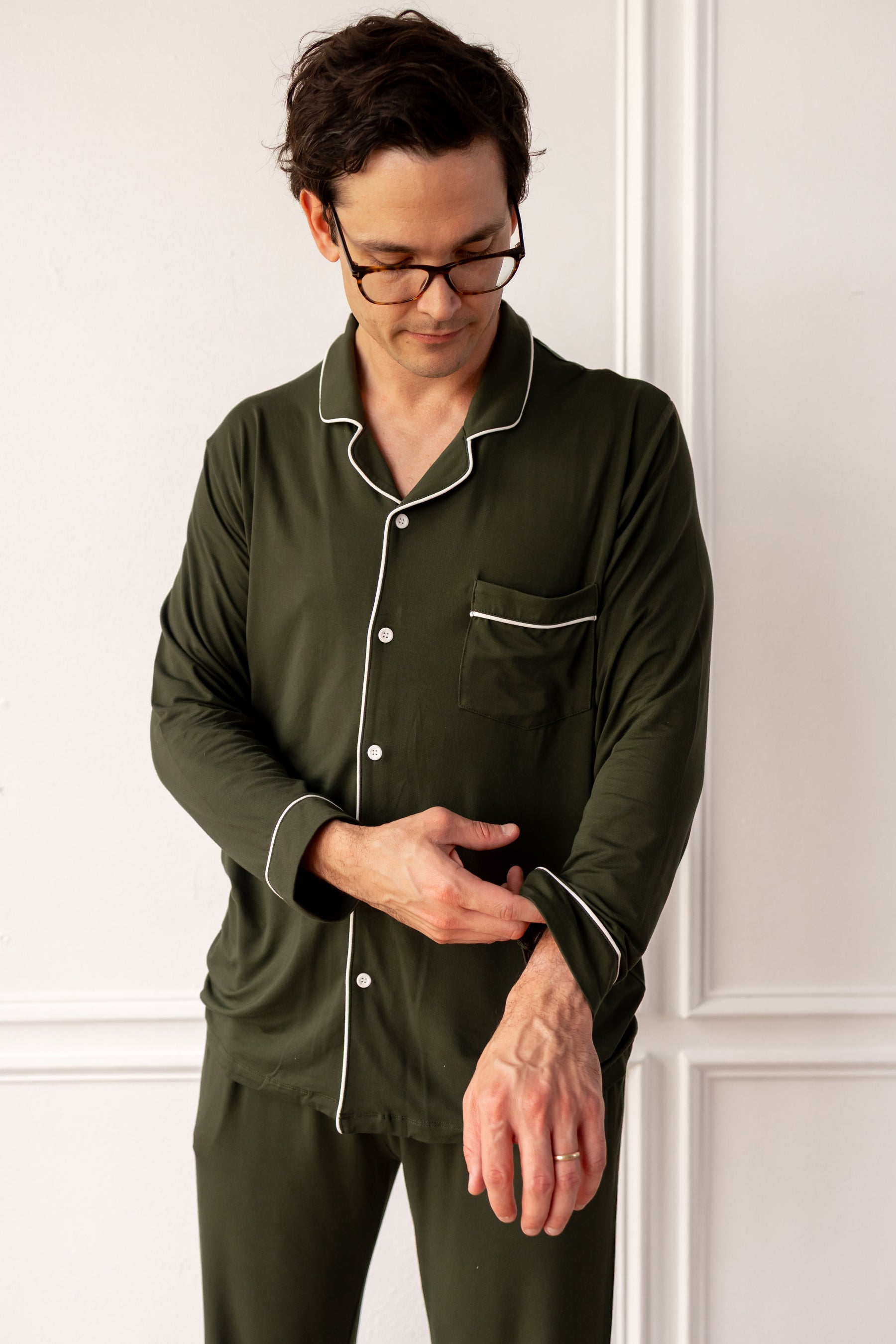 Person wearing green pajamas with white piping against a white wall