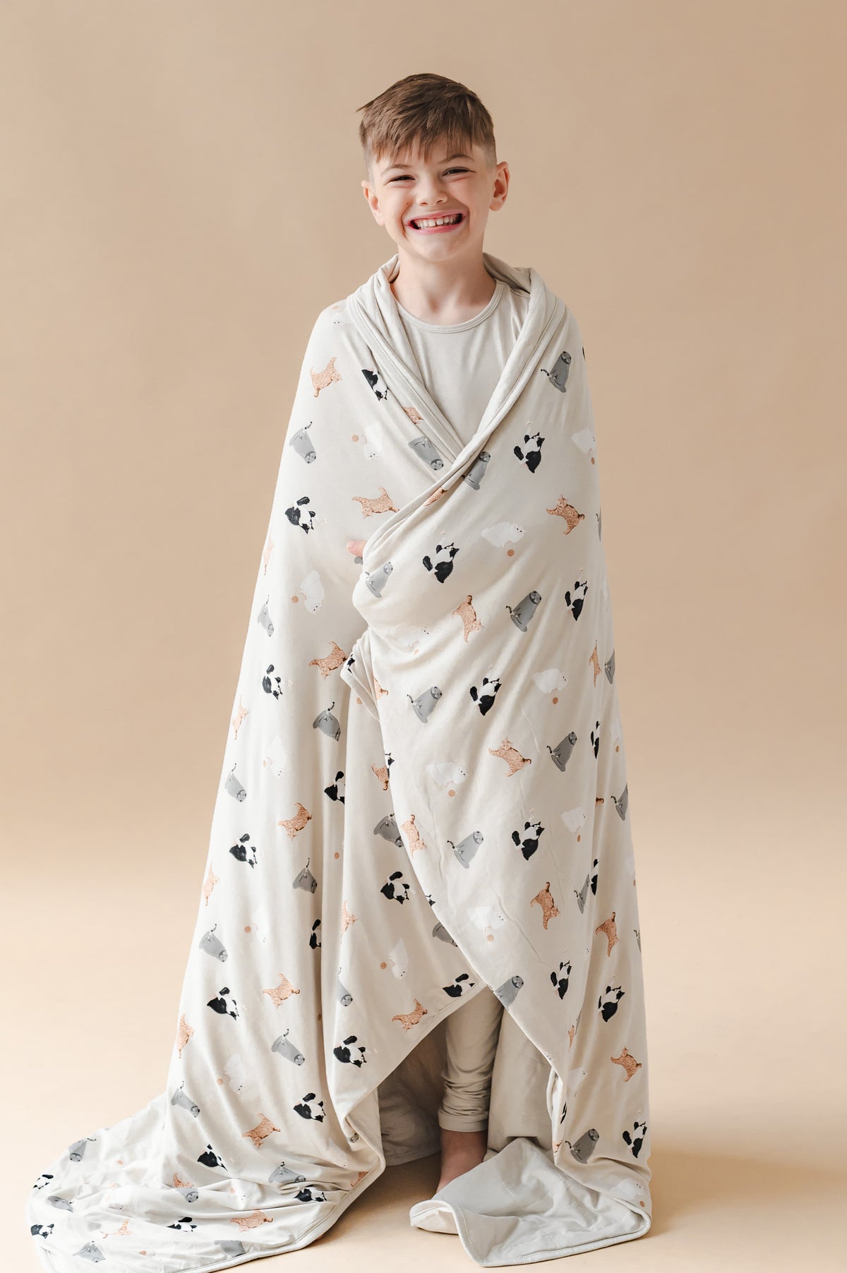 Boy wrapped in a throw blanket with a cat pattern