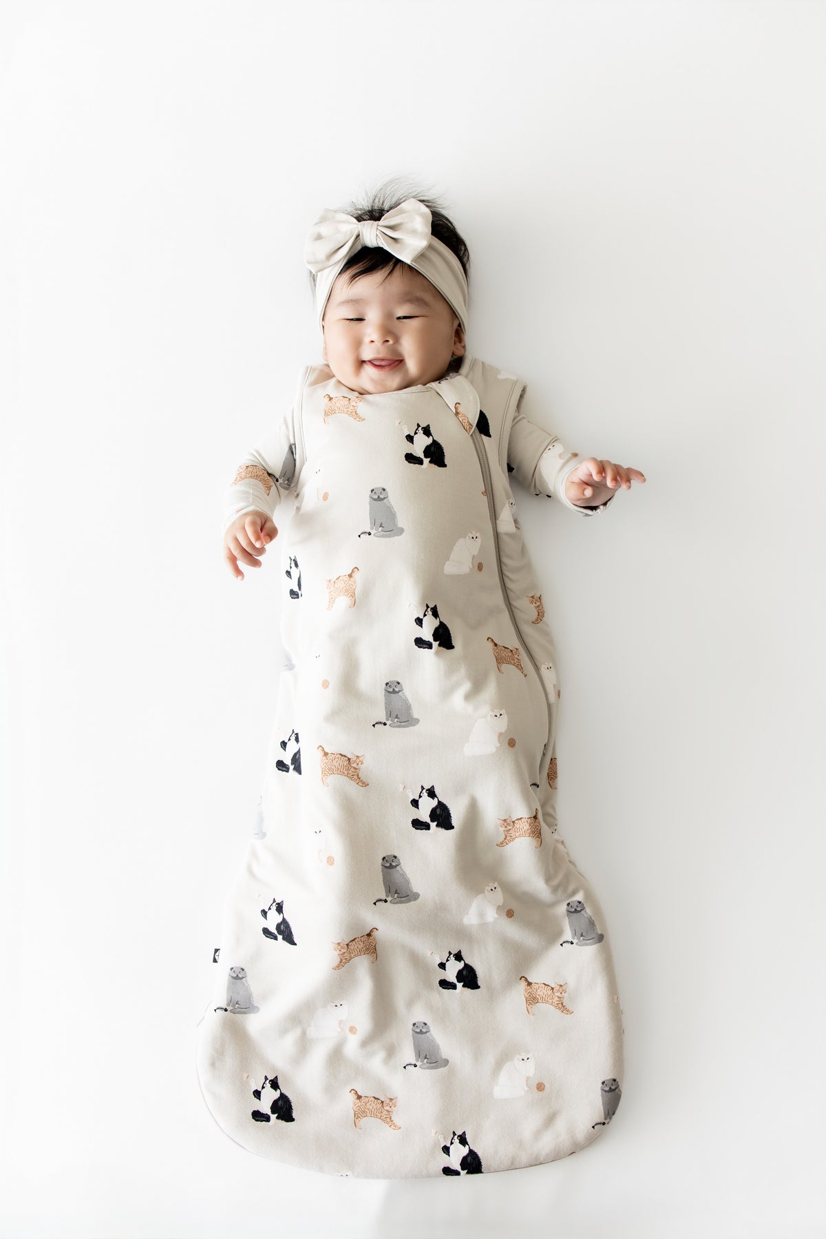 Smiling infant wearing he Sleep Bag in Fluffy Cat 1.0 with matching romper on underneath