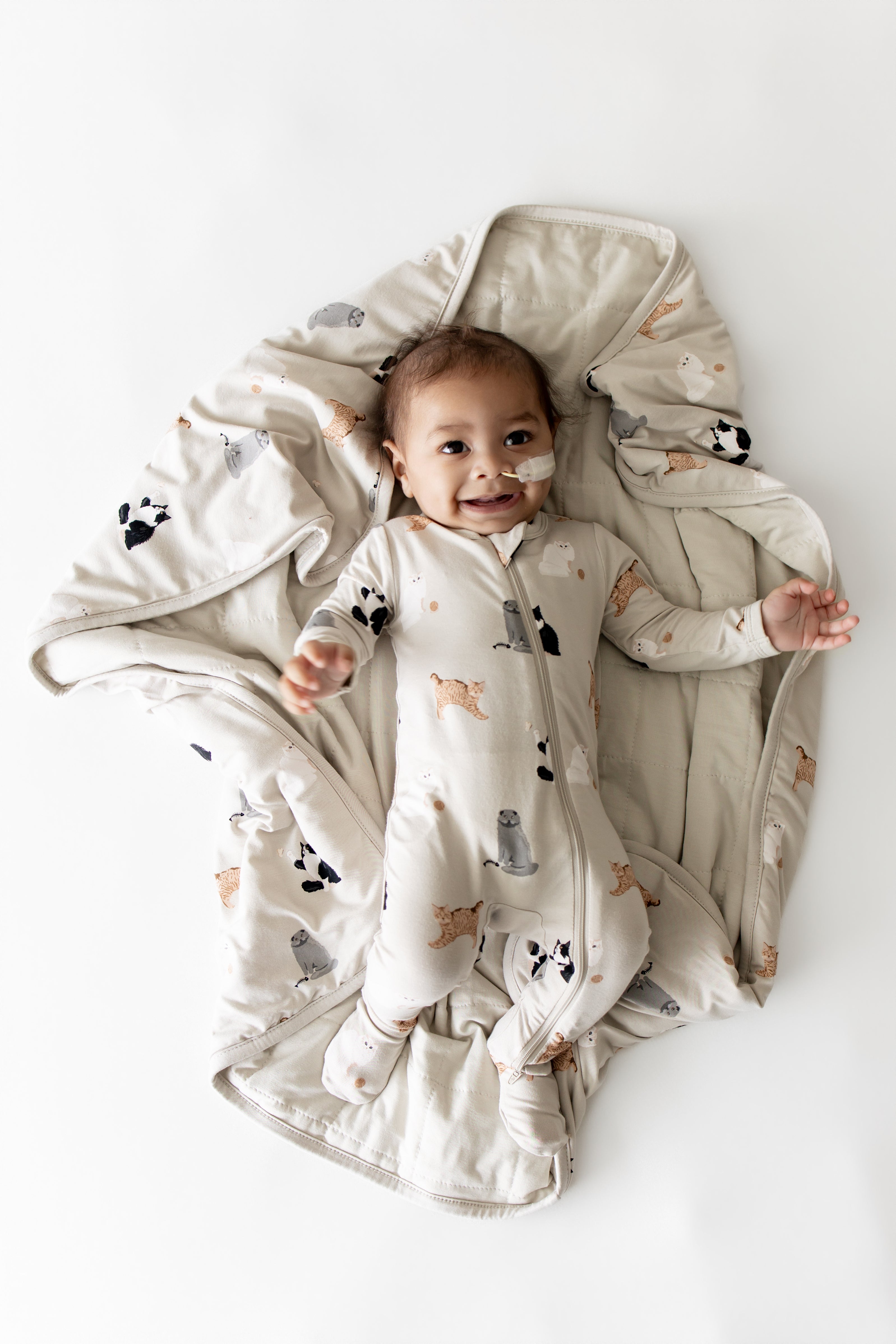 Smiling infant laying on a Baby Blanket in Fluffy Cat wearing a matching zippered footie