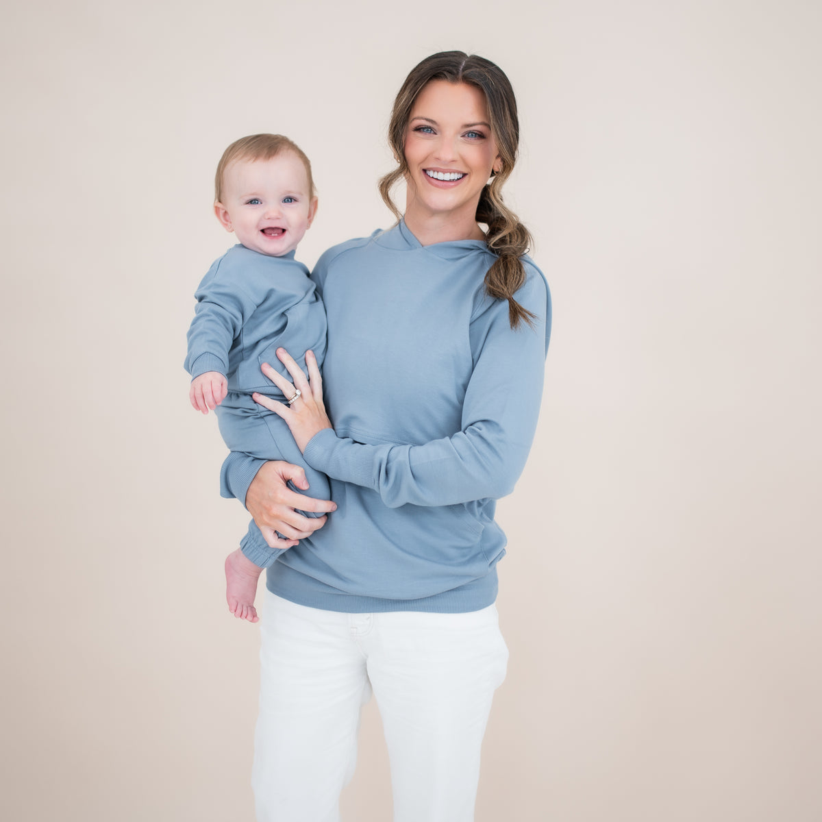 Smiling mother holding her smiling toddler both matching in Slate. Young child wearing the French Terry Jogger Set in Slate with mother wearing the French Terry Nursing hoodie