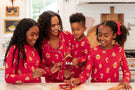 family of 4 in matching christmas gingerbread pajamas in a bright kitchen