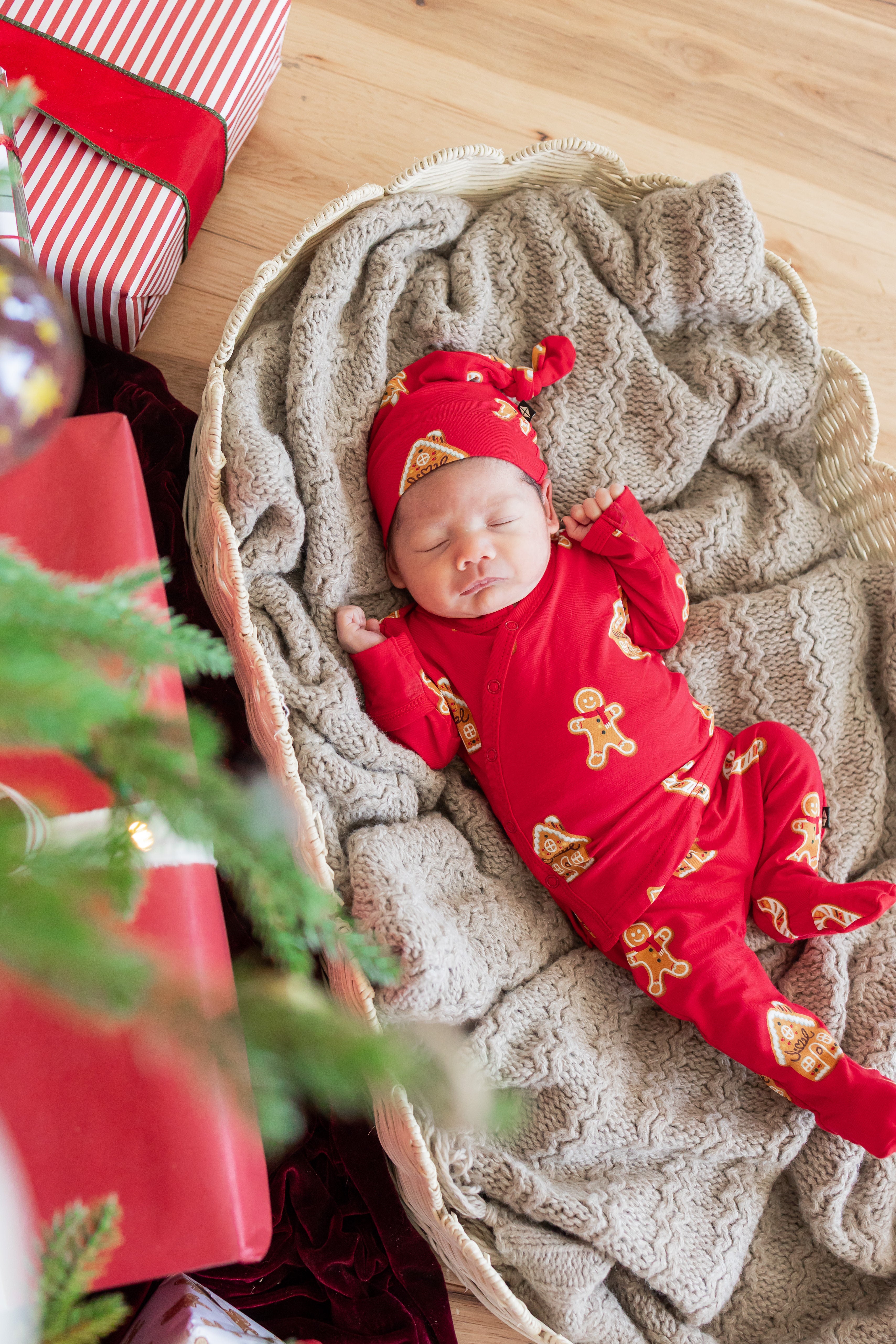 Baby wearing take me home set with cap in gingerbread print sleeping in a basket